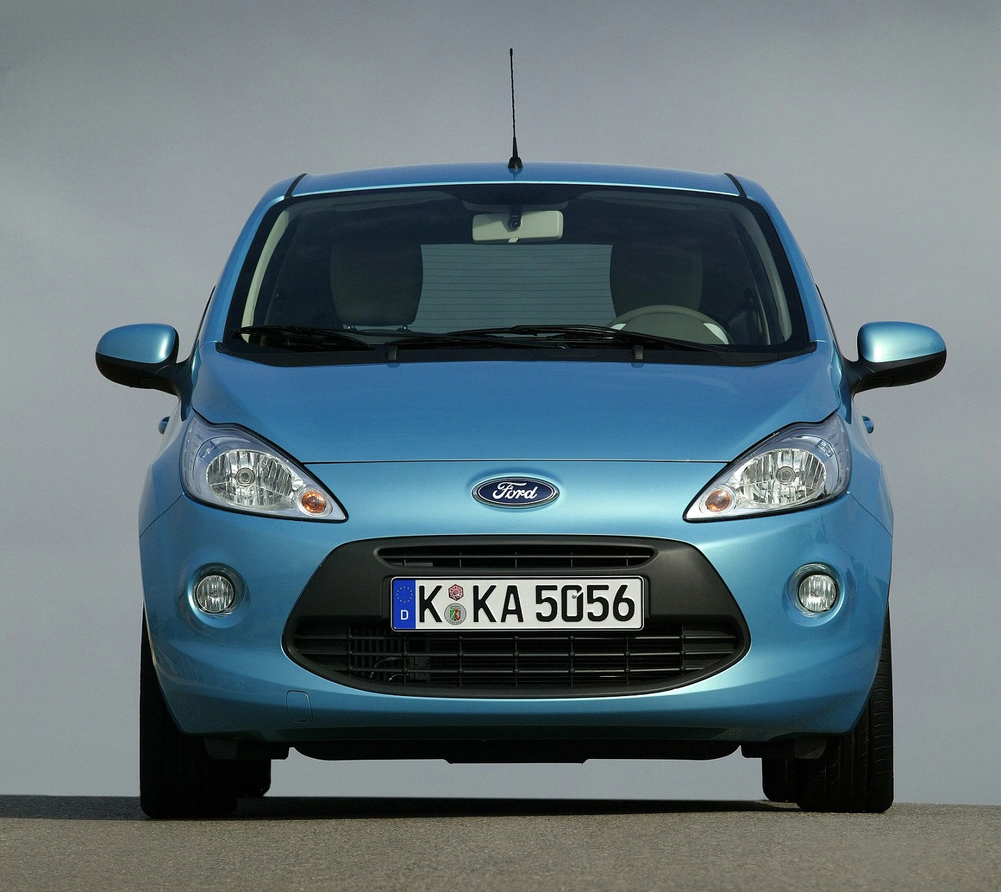 Blauer Ford Ka von vorne auf einer Straße, klarer Himmel im Hintergrund, deutsches Kennzeichen sichtbar.