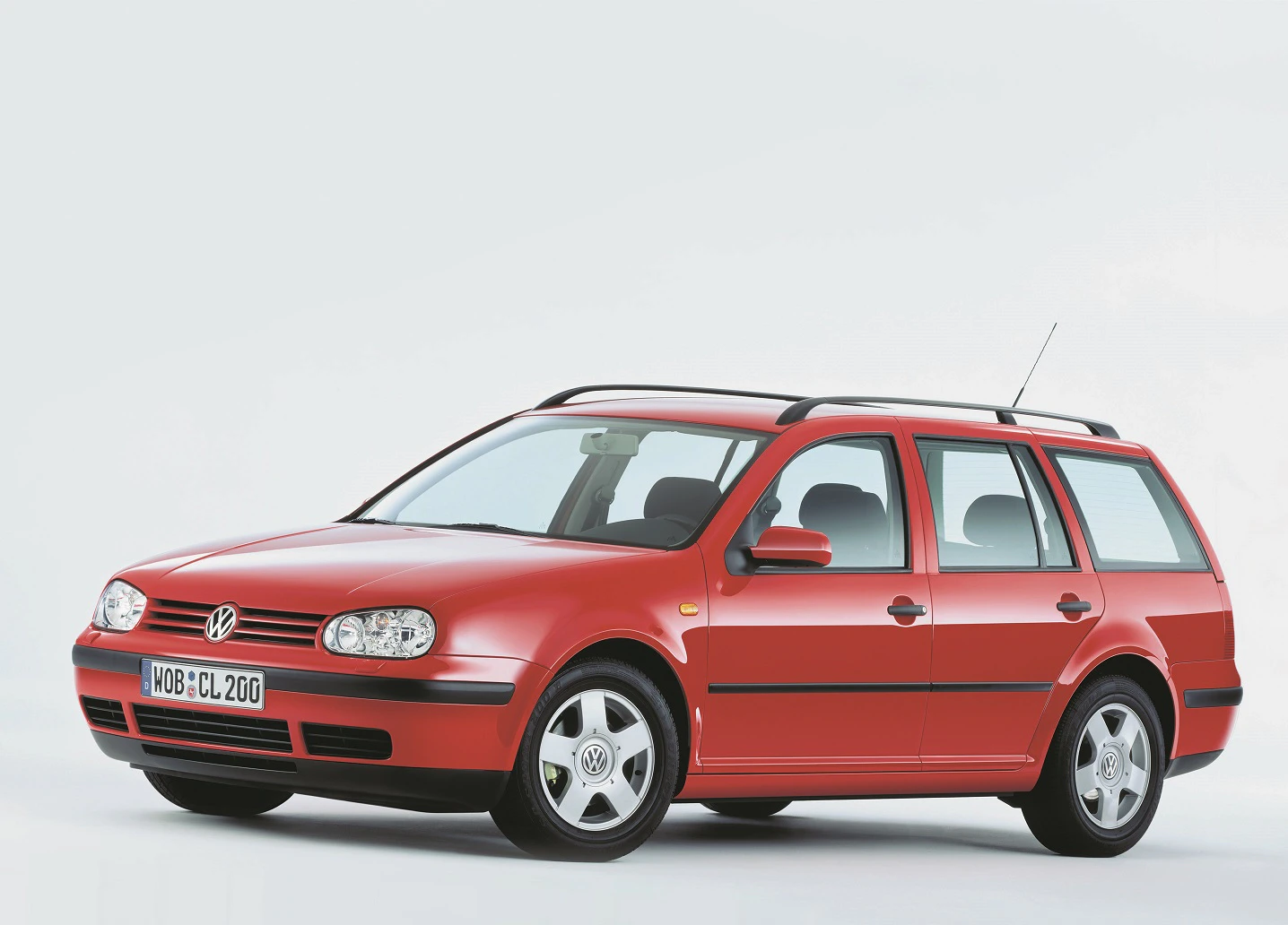 Roter Volkswagen Kombi auf weißem Hintergrund, seitliche Ansicht. Der Wagen hat vier Türen und ein europäisches Kennzeichen.