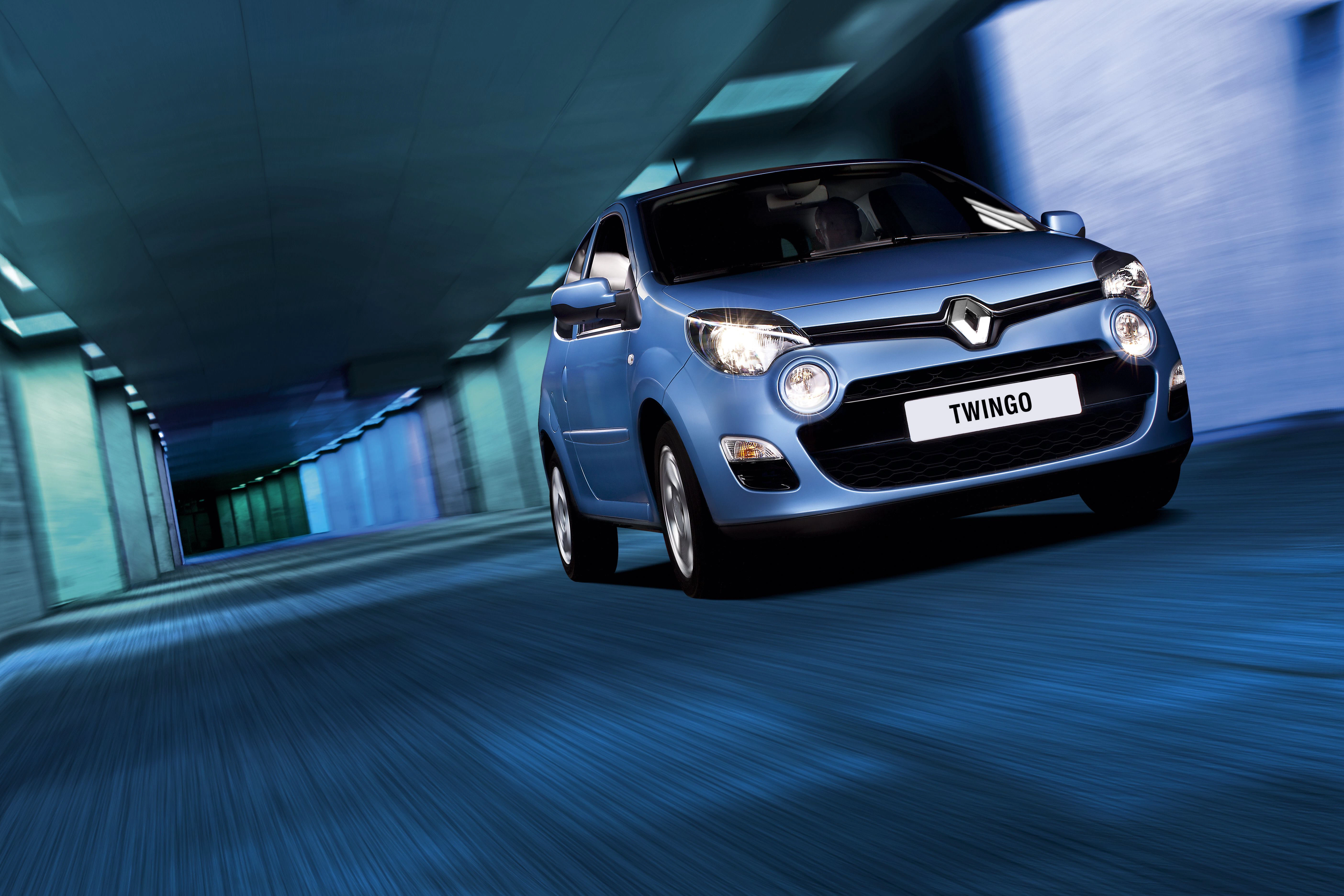 Blauer Renault Twingo fährt durch einen modernen Tunnel mit blauem Licht, in Bewegung vorwärts zeigend.