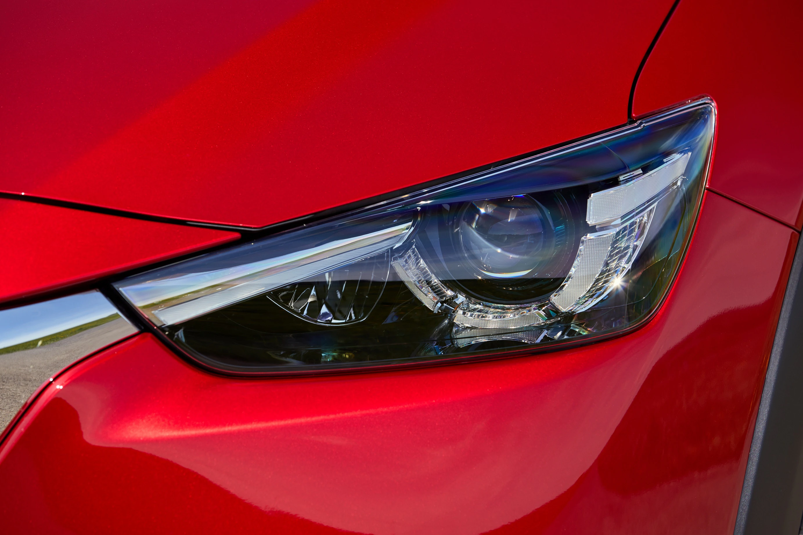 Nahaufnahme eines modernen, roten Autoscheinwerfers mit präzisem Design und glänzender Oberfläche.
