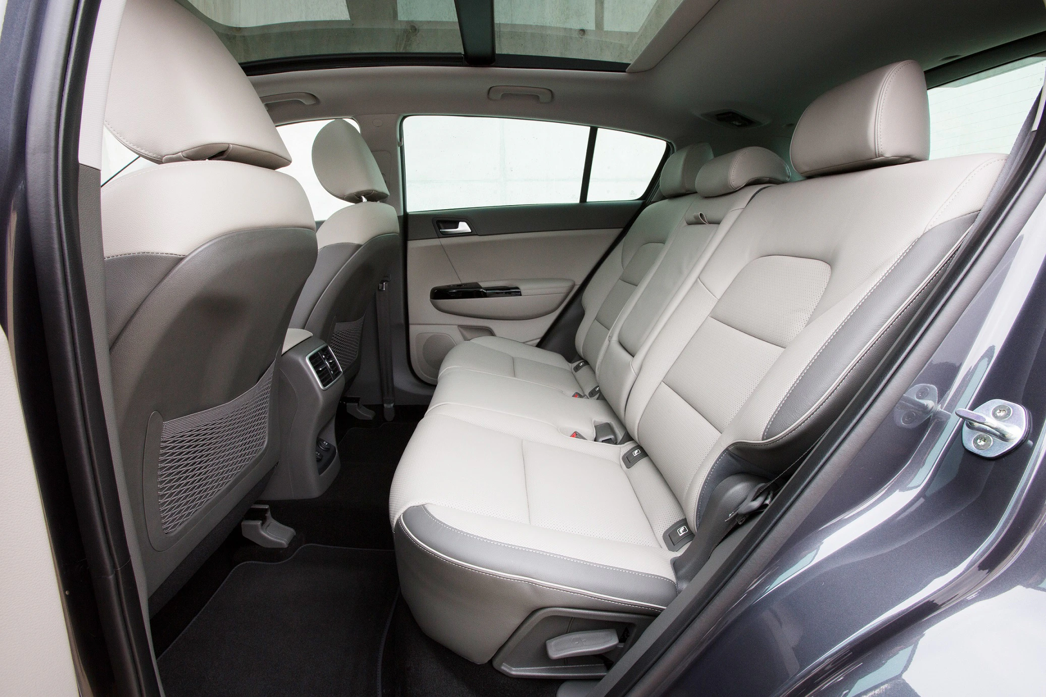 Innenraum eines Autos mit beigen Ledersitzen und viel Beinfreiheit, Blick von der hinteren rechten Tür.