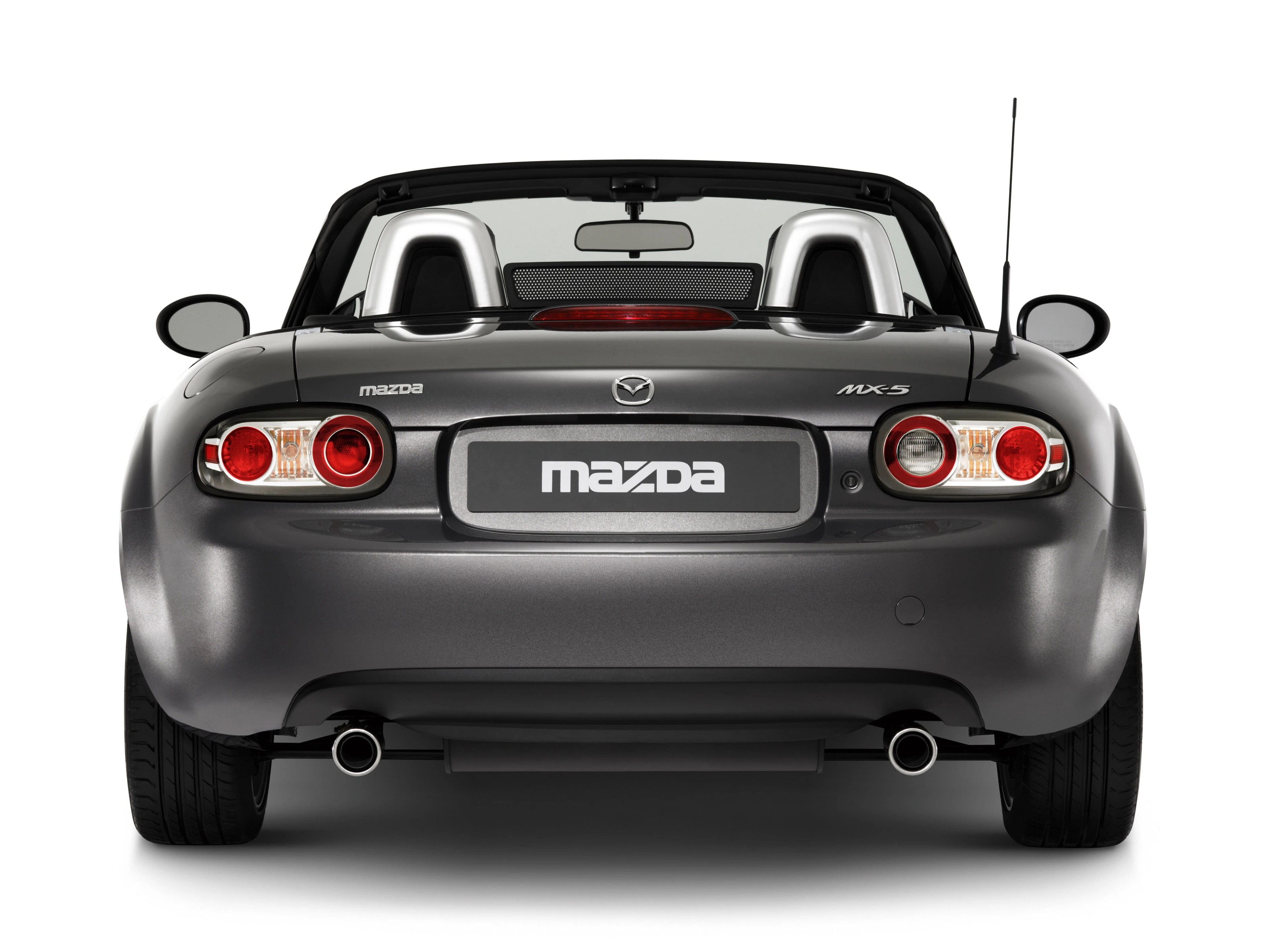 Rückansicht eines grauen Mazda MX-5 Cabrios. Sichtbar: Rücklichter, Auspuffrohre und das geöffnete Verdeck.