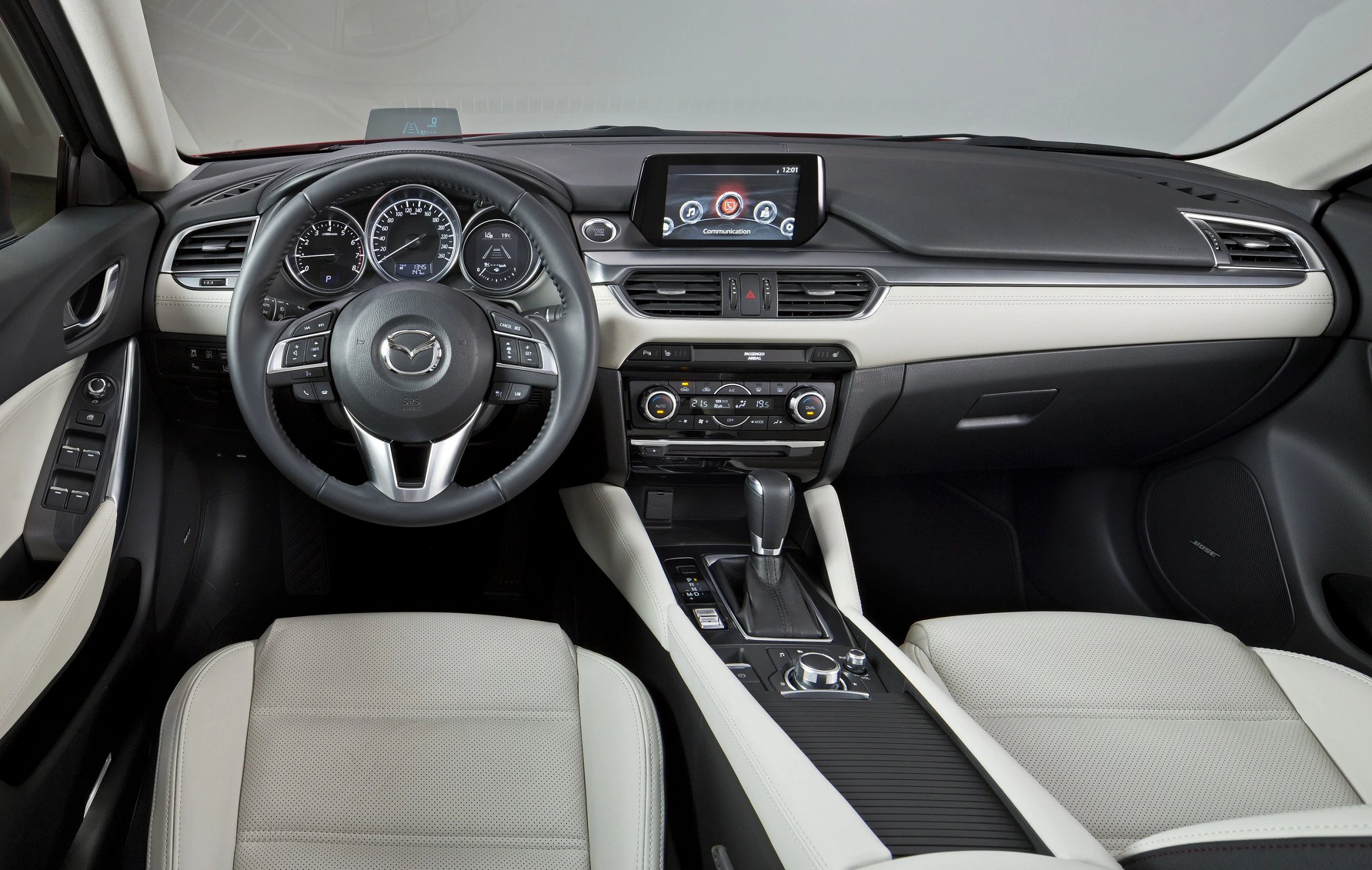 Innenraum eines Autos mit schwarzem Armaturenbrett, modernem Lenkrad, Touchscreen-Display und hellen Ledersitzen.