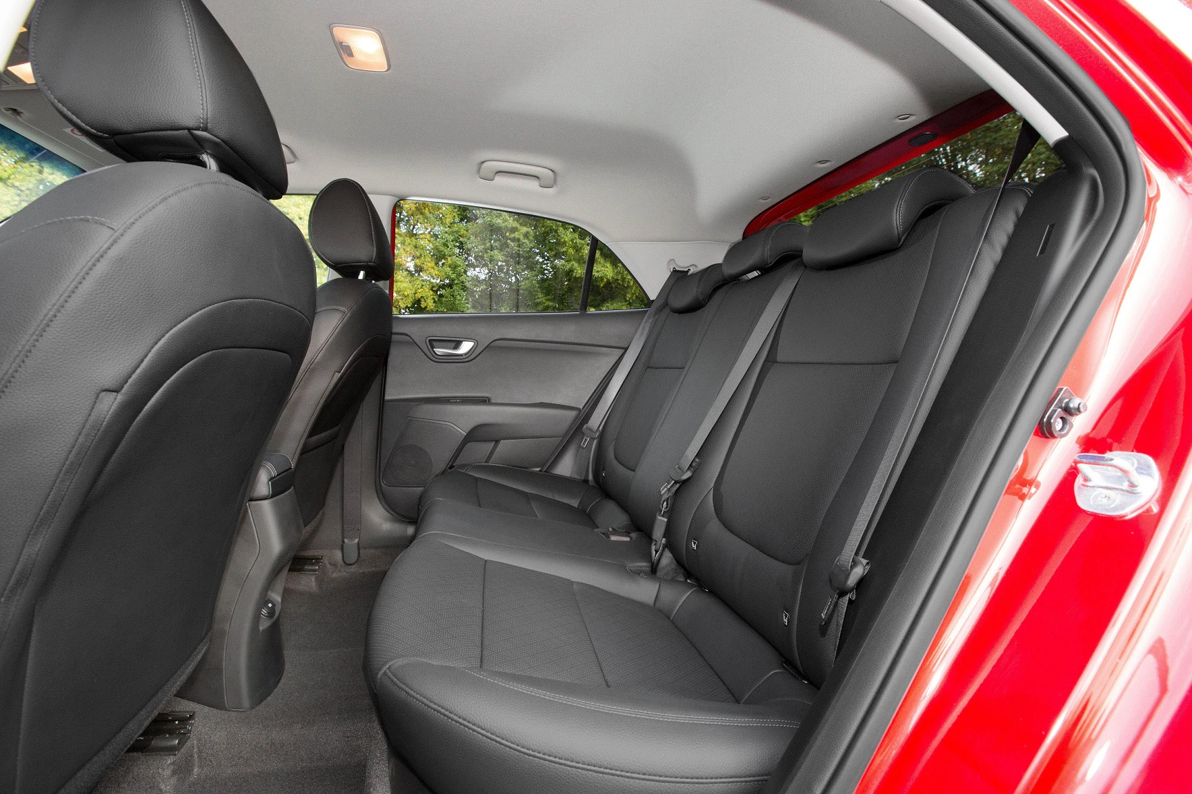 Rückbank eines roten Autos mit schwarzen Ledersitzen, Blick von der geöffneten Beifahrertür nach innen.