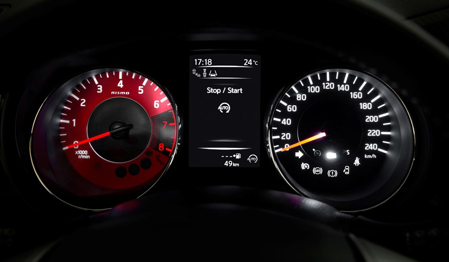 Tachometer eines Autos bei Nacht. Links Drehzahlmesser, rechts Geschwindigkeitsmesser und in der Mitte ein digitaler Bildschirm.