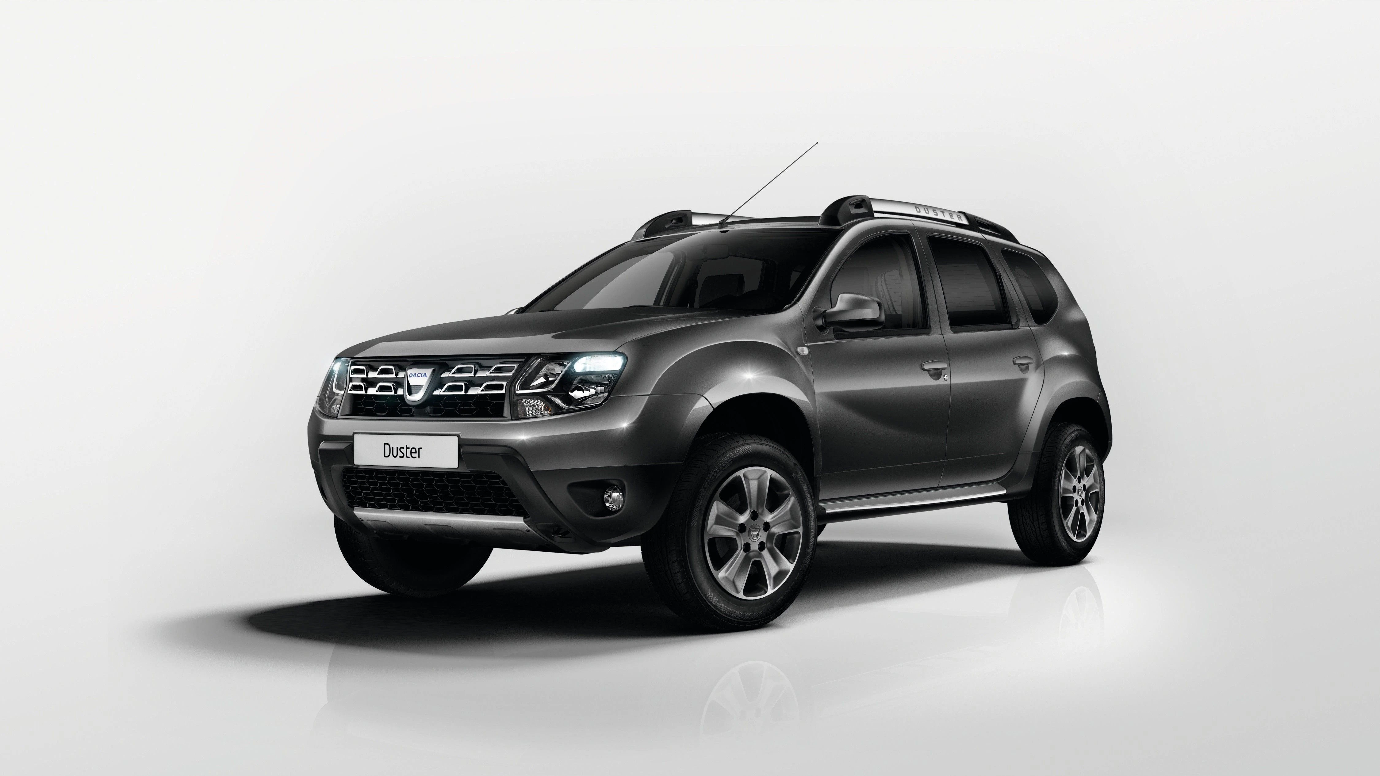 Grauer SUV auf weißem Hintergrund, Front- und Seitenansicht. Dachgepäckträger und markante Frontscheinwerfer sind sichtbar.