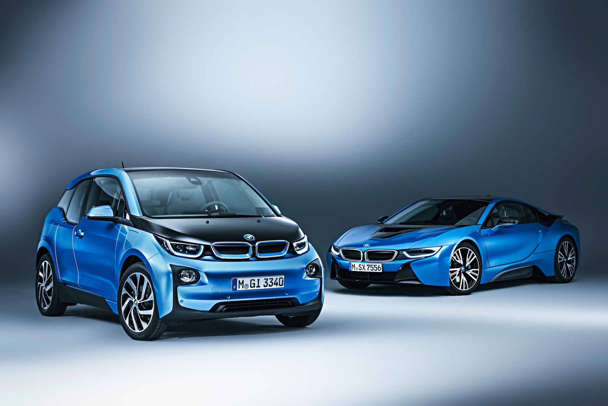 Zwei blaue BMW-Modelle stehen vor einem grauen Hintergrund: Ein kompakter i3 auf der linken Seite und ein sportlicher i8 auf der rechten Seite.