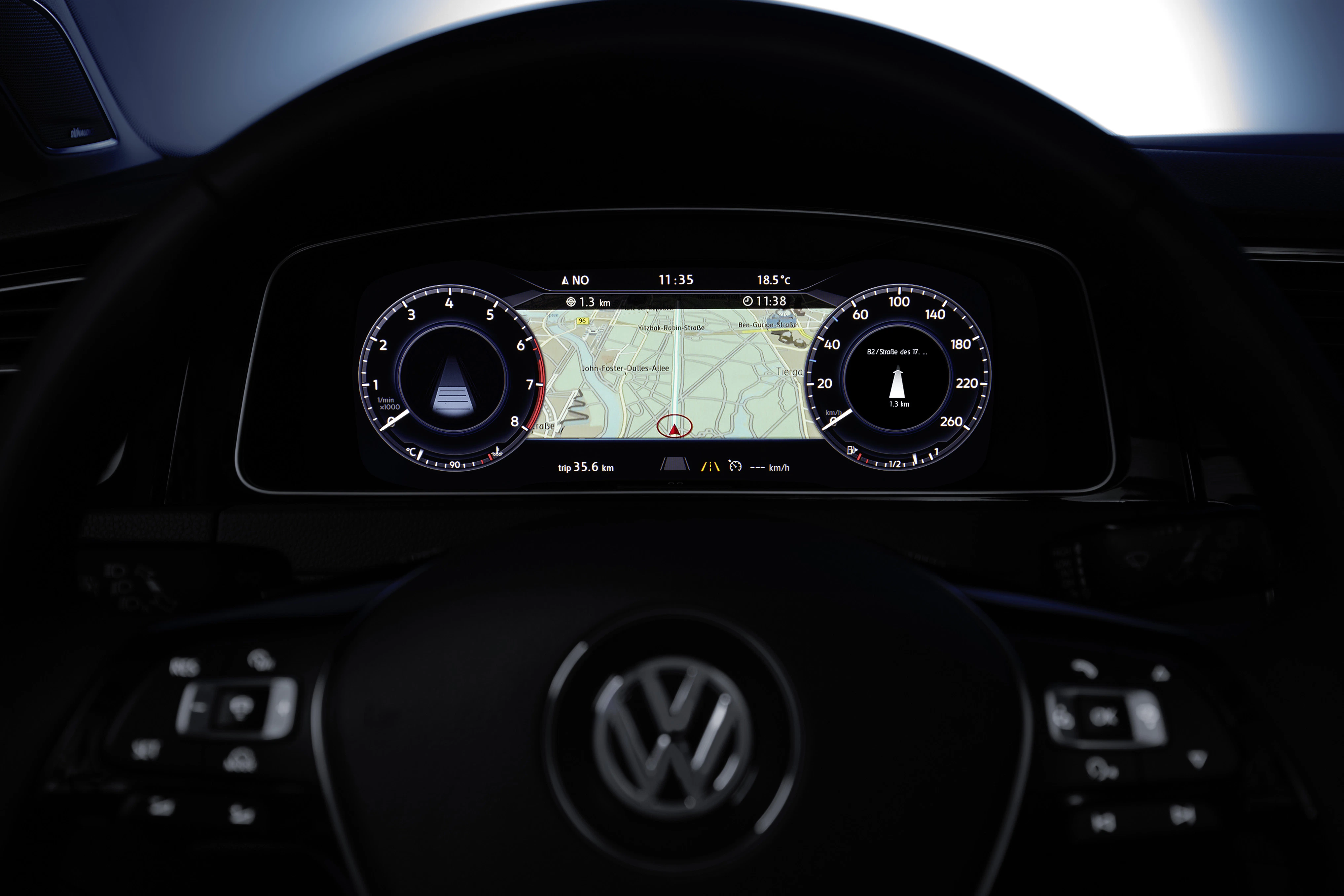 Nahaufnahme eines Volkswagen-Digitalcockpits mit Navigationsbildschirm und analogem Tacho. Lenkrad mit VW-Logo ist zu sehen.