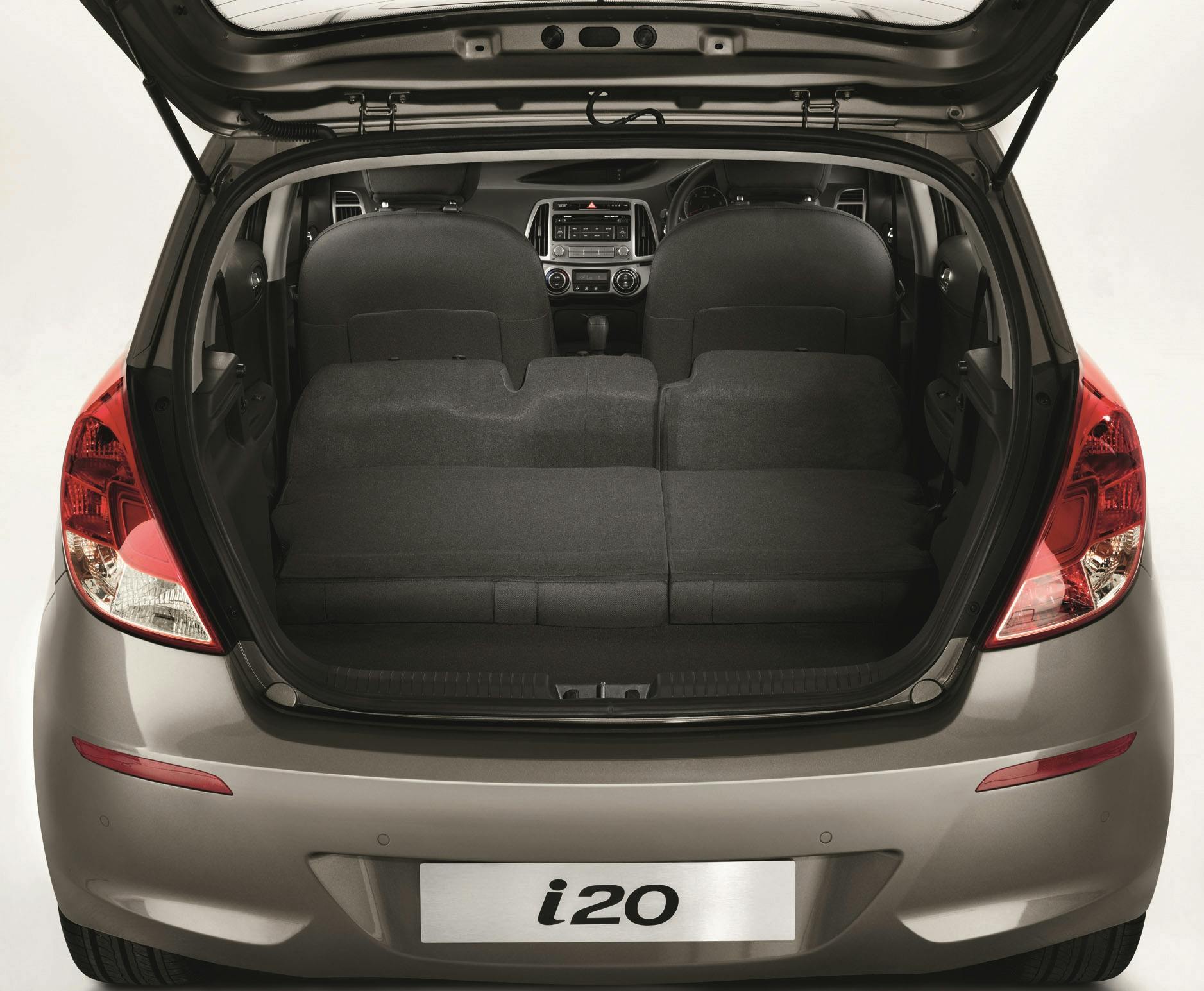 Offener Kofferraum eines grauen Autos mit umgeklappten Rücksitzen, Sicht auf Innenraum und Armaturenbrett.