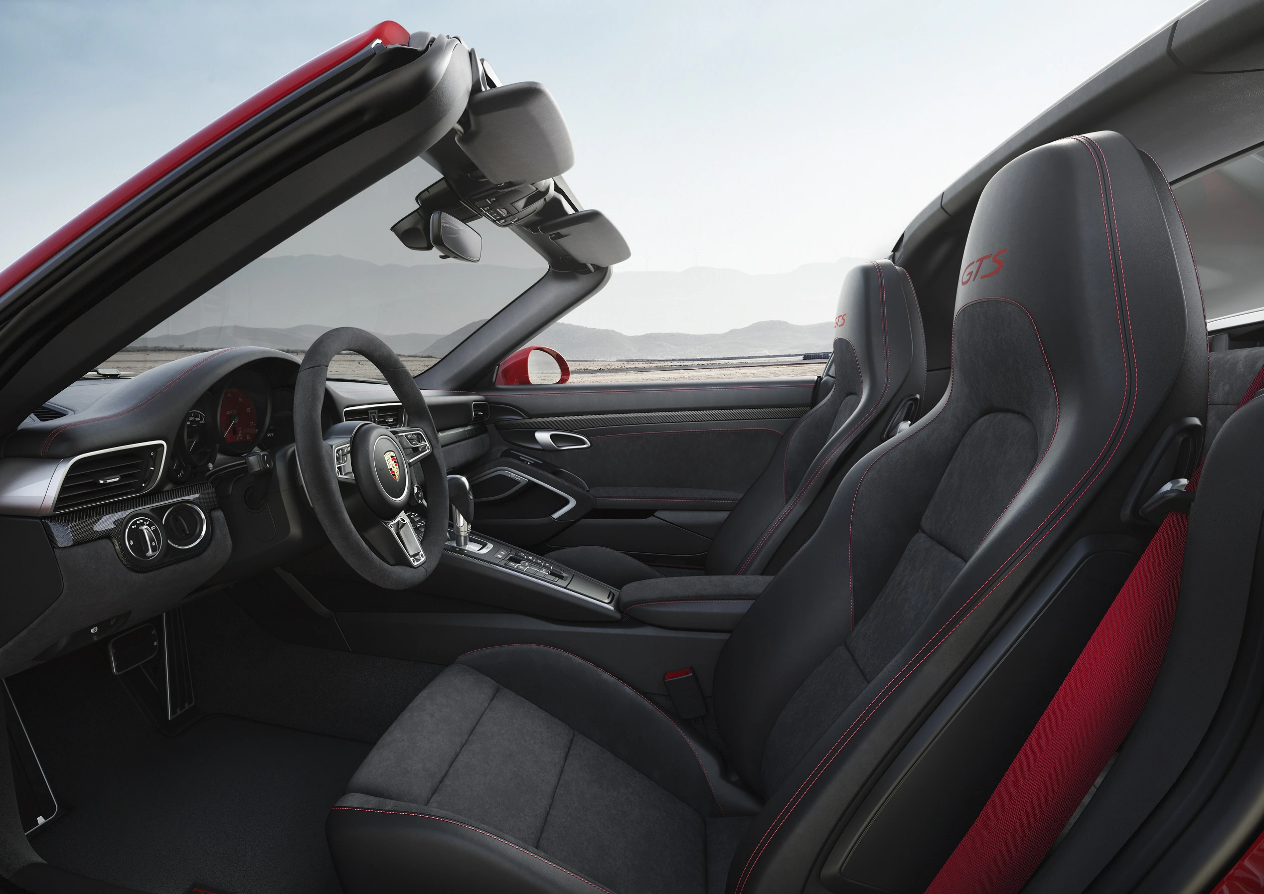 Innenraum eines sportlichen Cabriolets mit schwarzen Ledersitzen und roten Nähten, elegantes Design, Lenkrad und Armaturenbrett sichtbar.