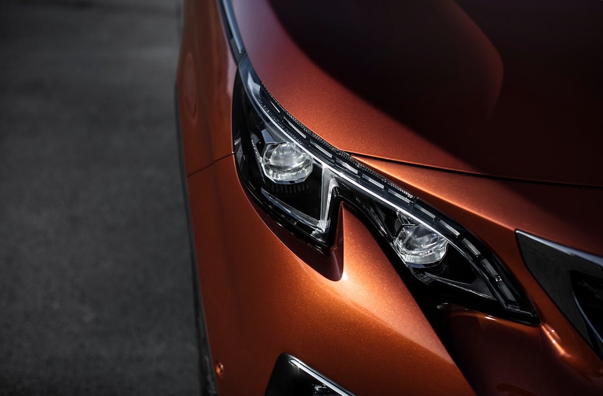 Nahaufnahme eines orangefarbenen Autoscheinwerfers mit elegantem, modernem Design auf dunklem Hintergrund.