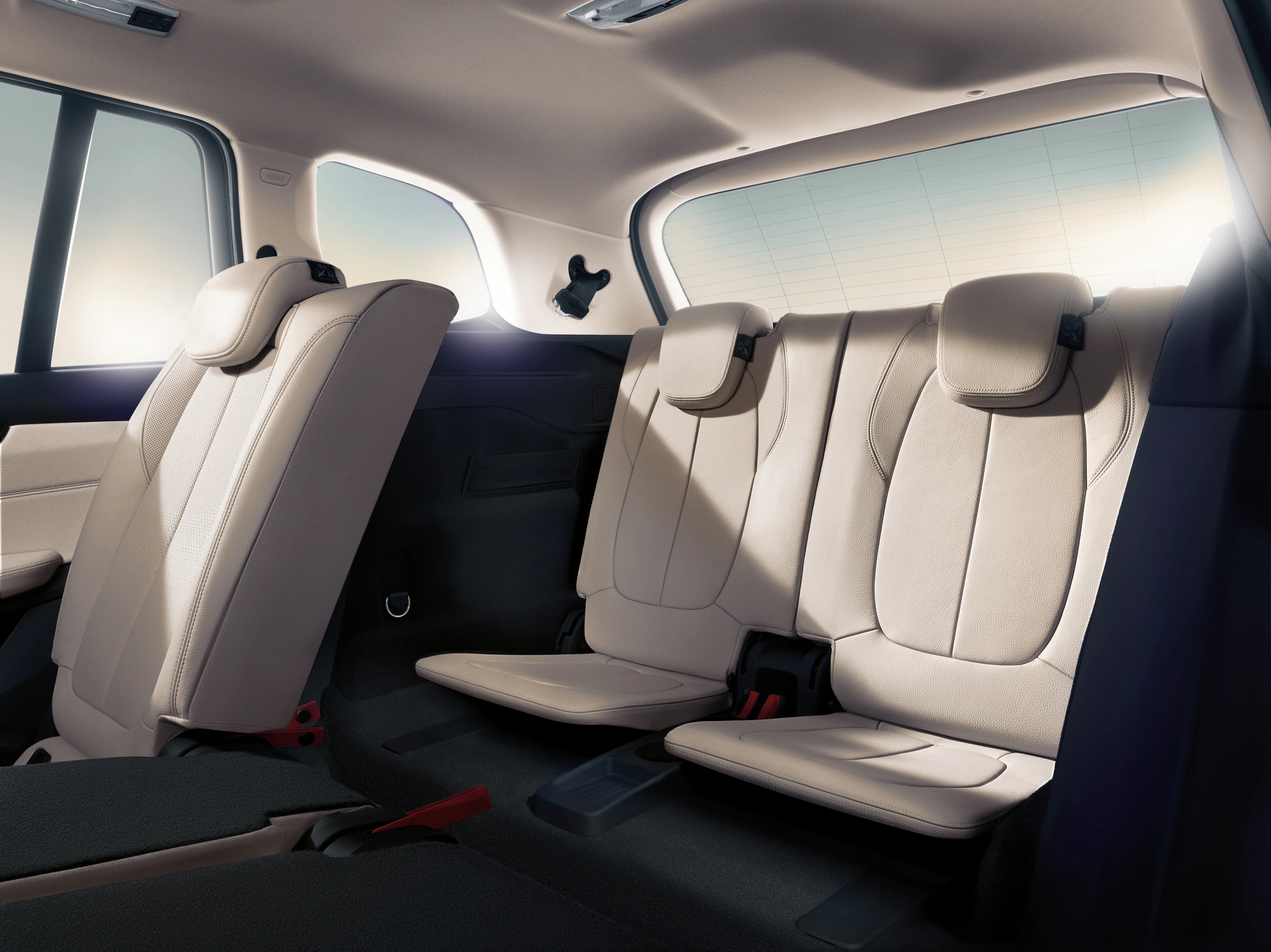 Innenraum eines Autos mit beiger Lederausstattung. Drei Sitzreihen, mittlere und hintere Sitze für zwei Personen. Modernes Design.