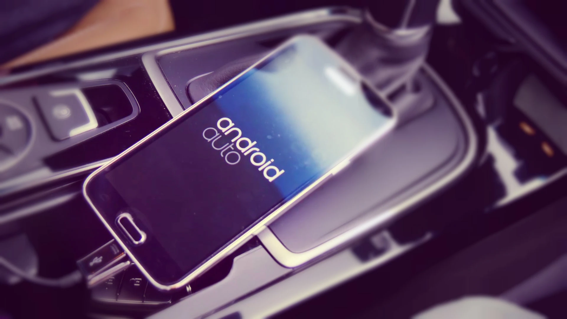 Smartphone mit Android Auto-Bildschirm liegt auf der Mittelkonsole eines Autos.