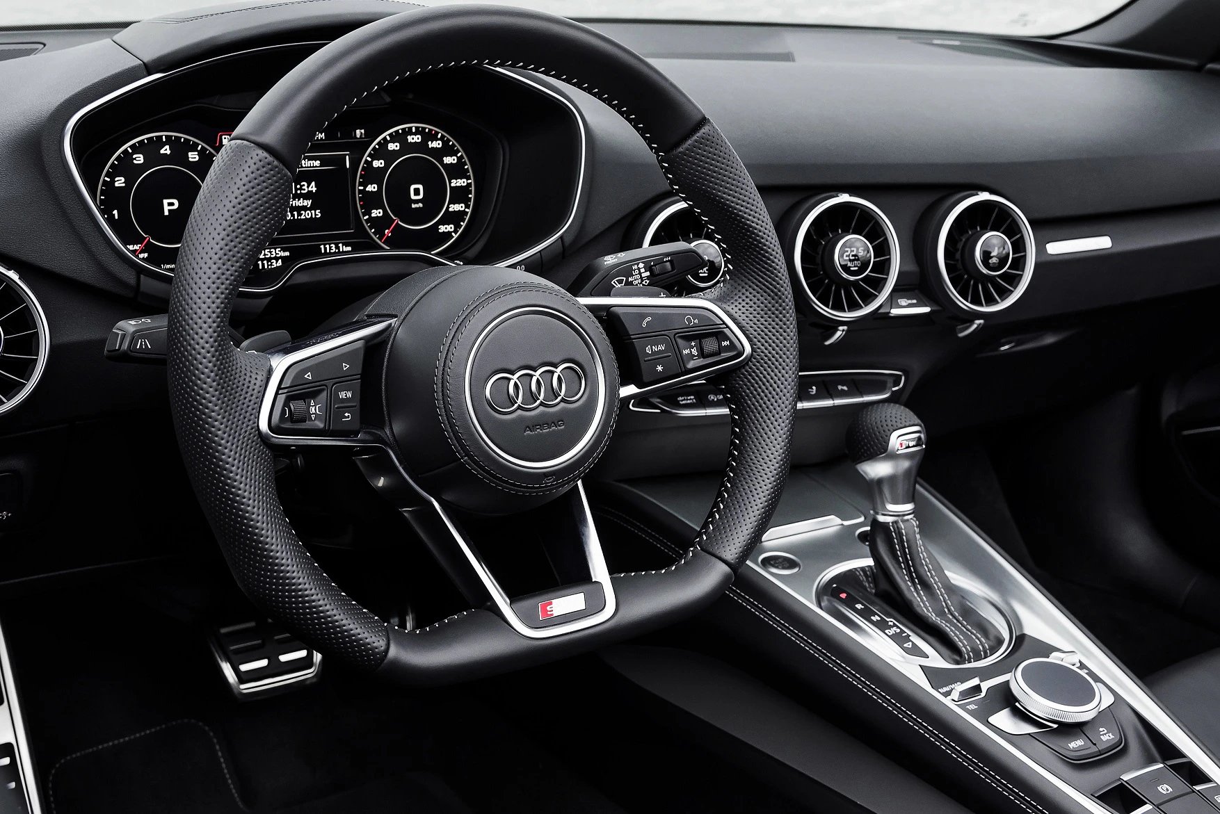 Innenraum eines Audi mit schwarzem Lederlenkrad, digitalen Armaturen und modernen Lüftungsauslässen, Automatikschaltung sichtbar.