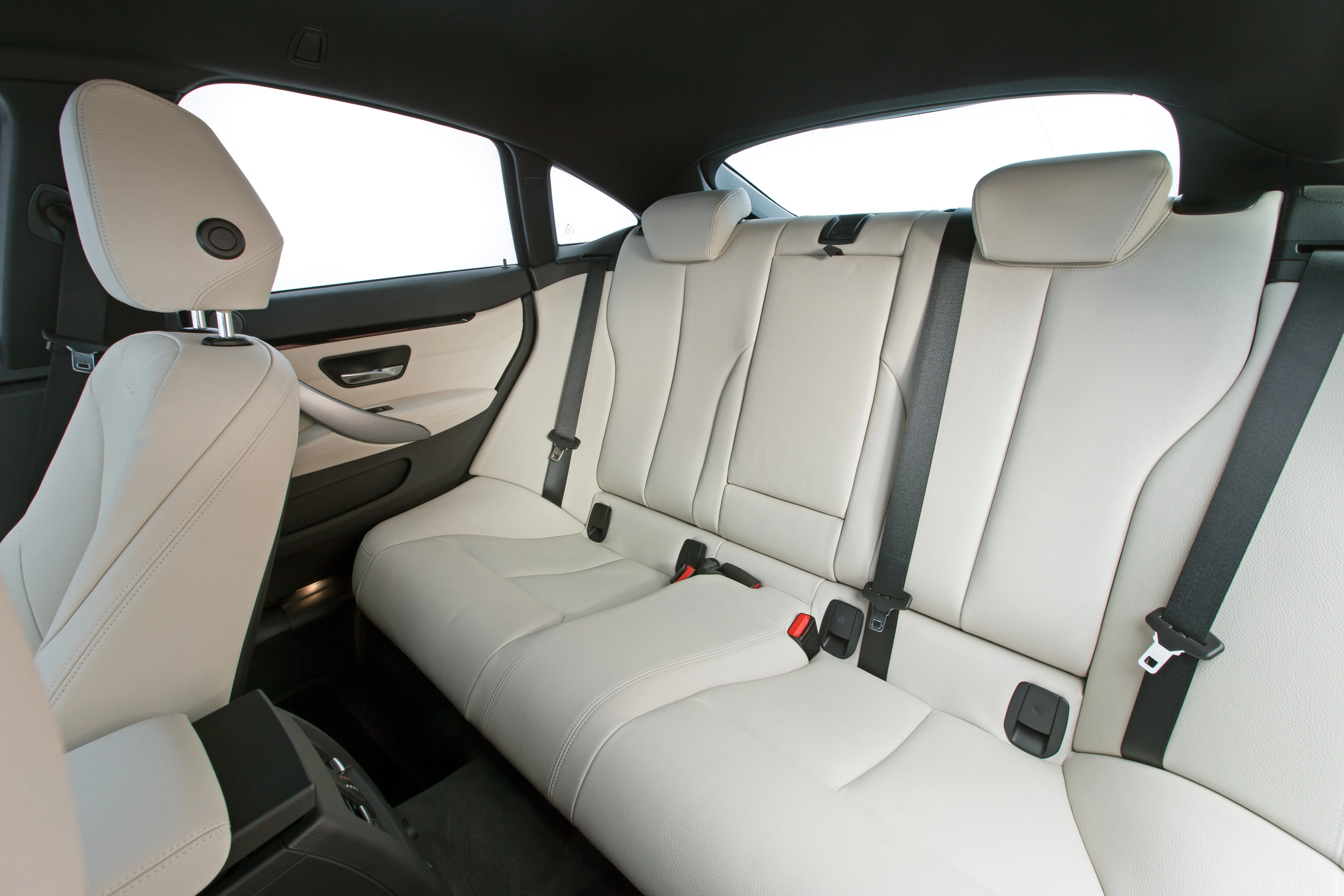 Rückansicht eines Autos mit beigem Ledersitz, drei Kopfstützen und Sicherheitsgurten, elegant und modern gestaltet.