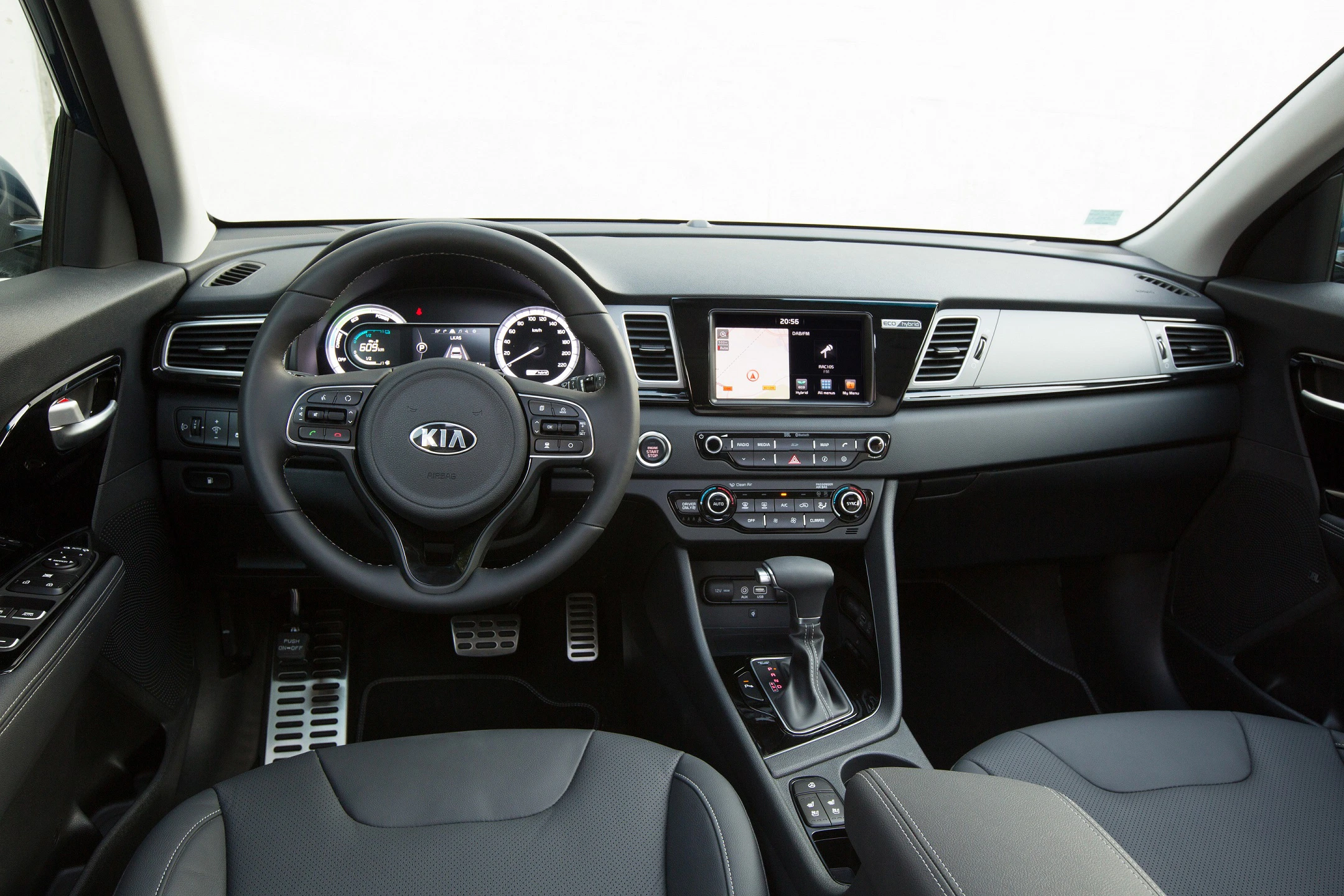 Innenraum eines KIA-Autos mit Lenkrad, Tachometer, Touchscreen-Display und Schalthebel. Moderne, schwarze Innenausstattung.