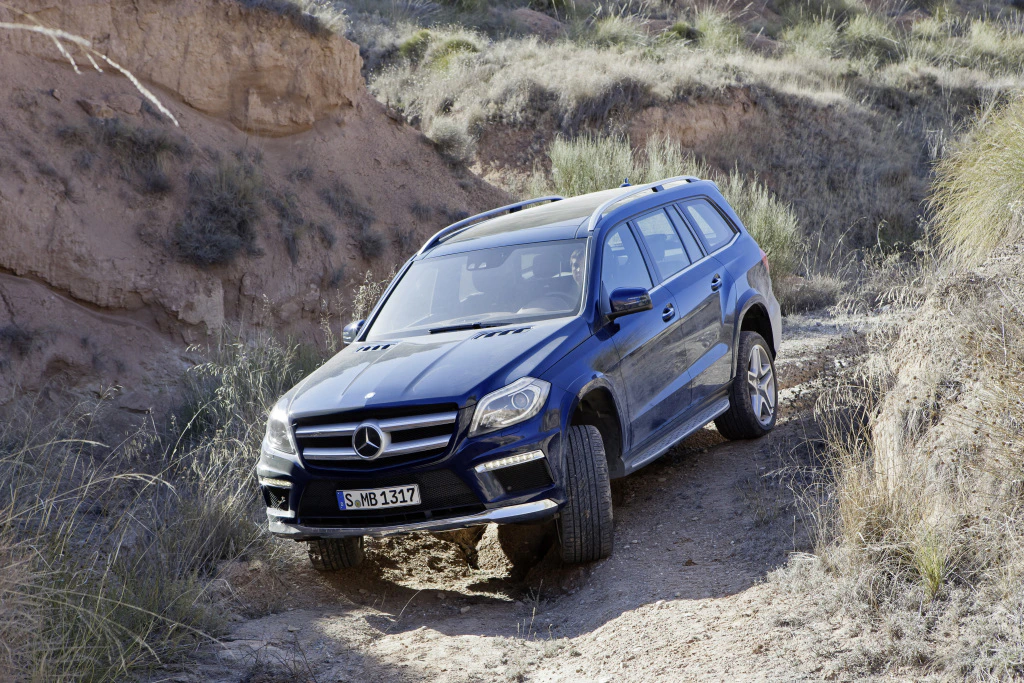 Blauer Mercedes-Geländewagen fährt auf einer steinigen, unebenen Piste in einer felsigen Landschaft bergauf.