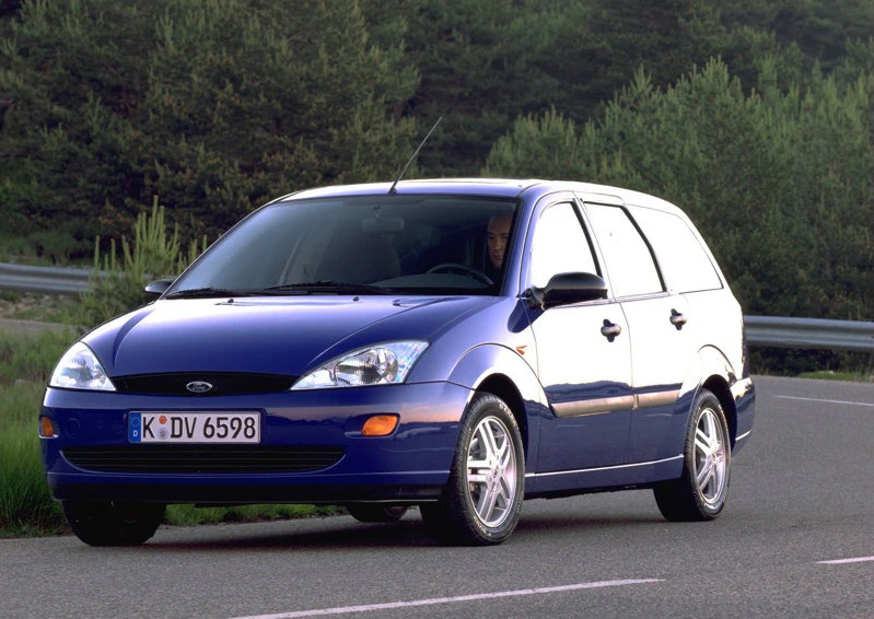Blauer Ford Focus Kombi fährt auf einer Landstraße, umgeben von Bäumen. Der Himmel ist klar, die Straße kurvig.