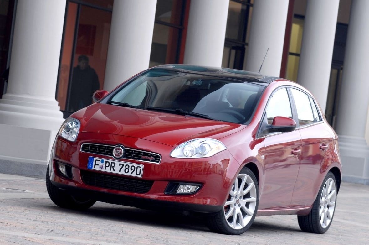 Roter Fiat Bravo parkt vor einem Gebäude mit Säulen. Der Wagen hat ein deutsches Kennzeichen und silberne Felgen.