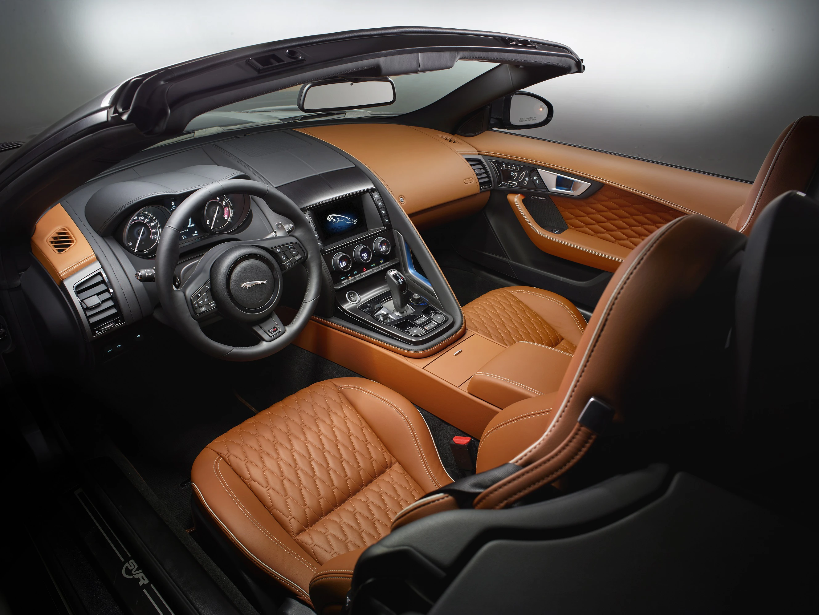 Innenraum eines luxuriösen Cabriolets mit braunen Ledersitzen, modernem Armaturenbrett und sportlichem Lenkrad, elegant und stilvoll.