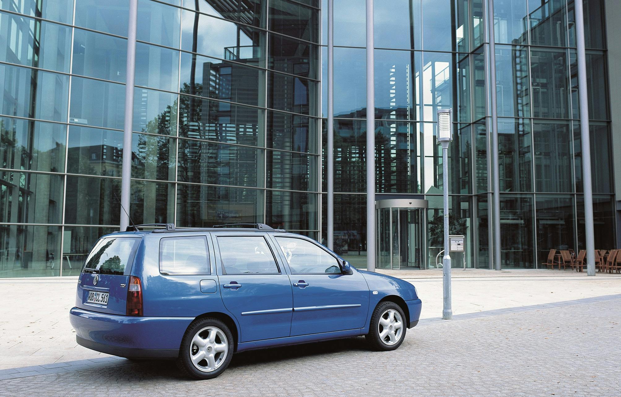 Blauer Kombi auf gepflastertem Platz vor einem modernen, verglasten Gebäude bei Tageslicht abgestellt.