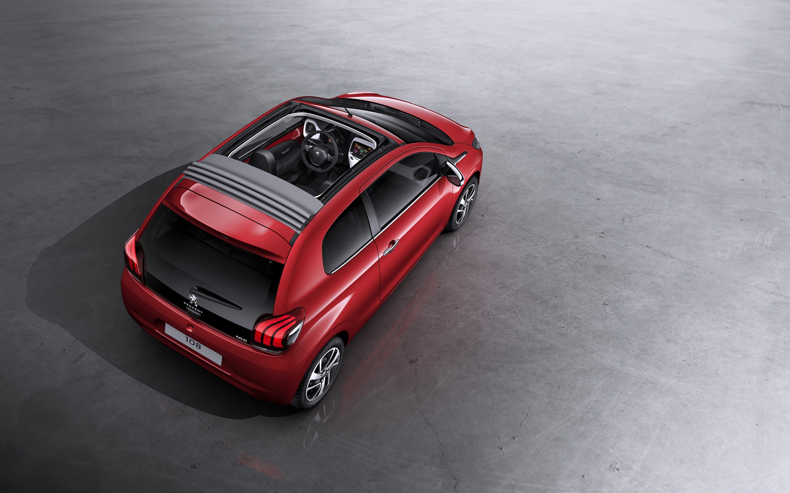 Roter Peugeot mit Panoramadach auf grauem Boden, aus der Vogelperspektive fotografiert.