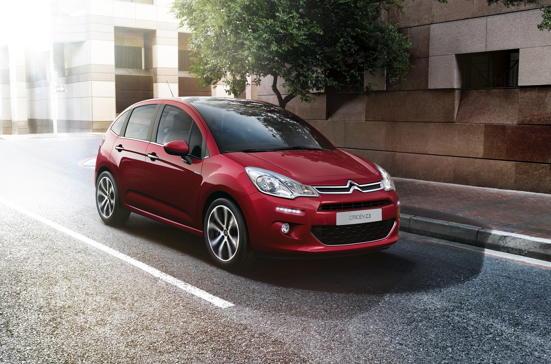 Roter Citroën C3 parkt auf leerer Stadtstraße vor modernen Gebäuden bei Tageslicht.