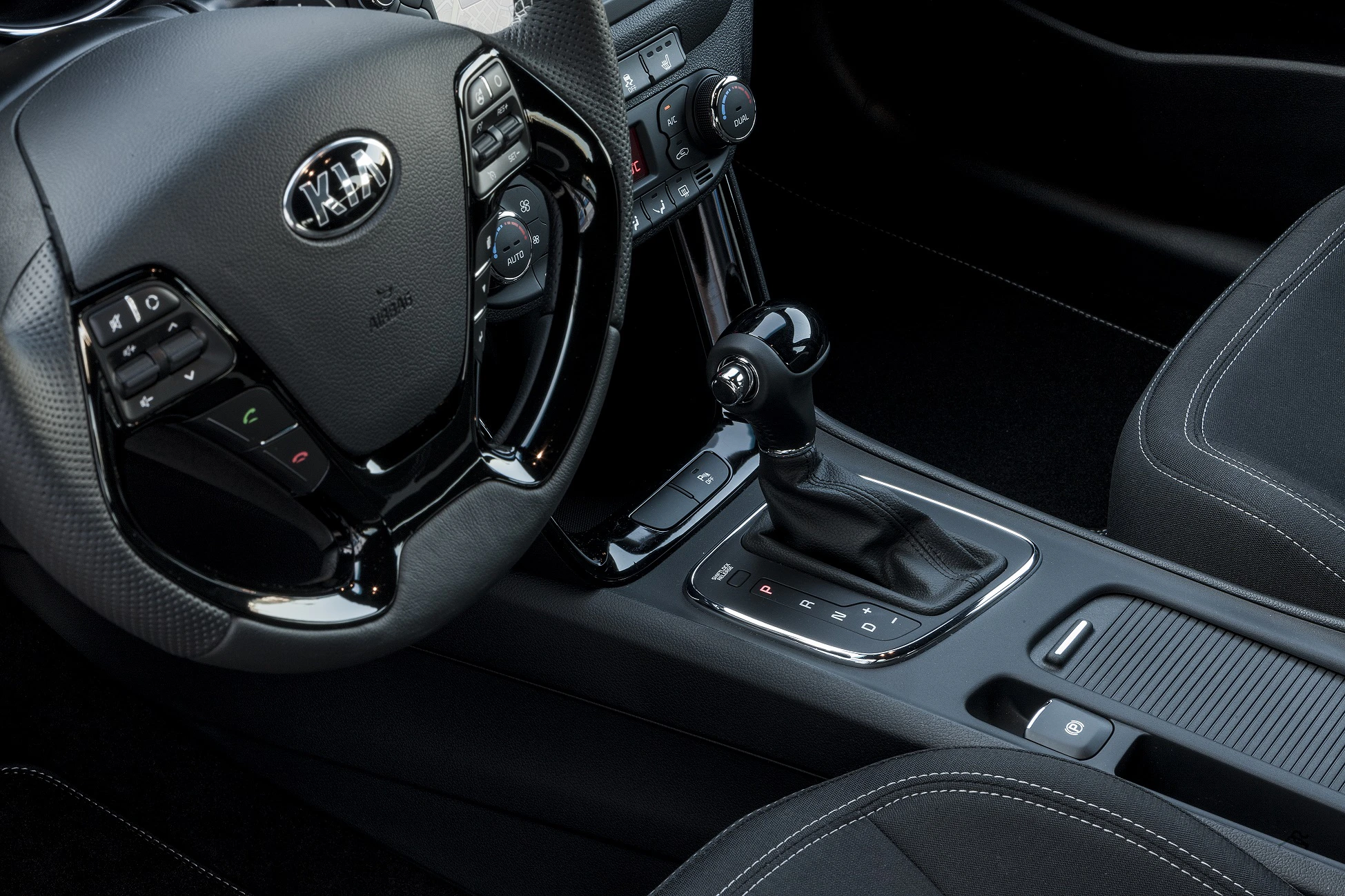 Innenansicht eines Autos mit detailiertem Blick auf das Lenkrad und den Automatik-Schalthebel in der Mittelkonsole.