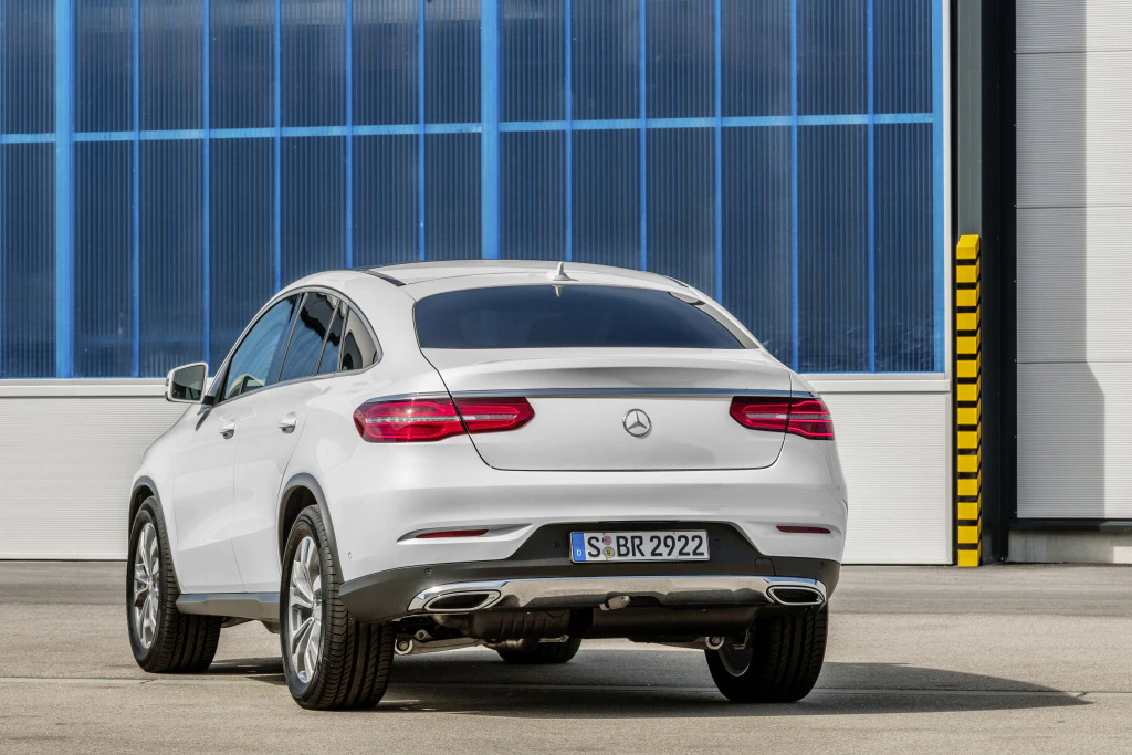 Ein weißer Mercedes-SUV steht vor einem blauen Gebäude, von hinten fotografiert.