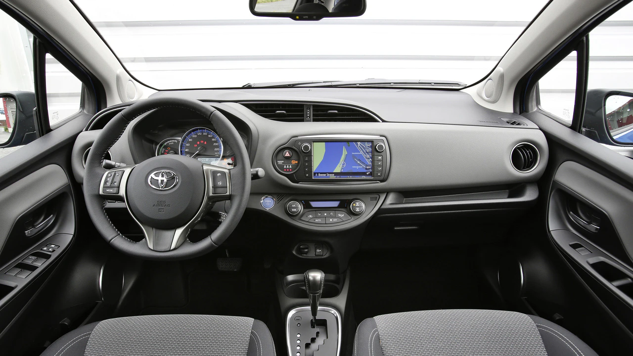 Innenraum eines Autos mit grauem Armaturenbrett, Lenkrad, Touchscreen-Navigationssystem und Automatikgetriebe.