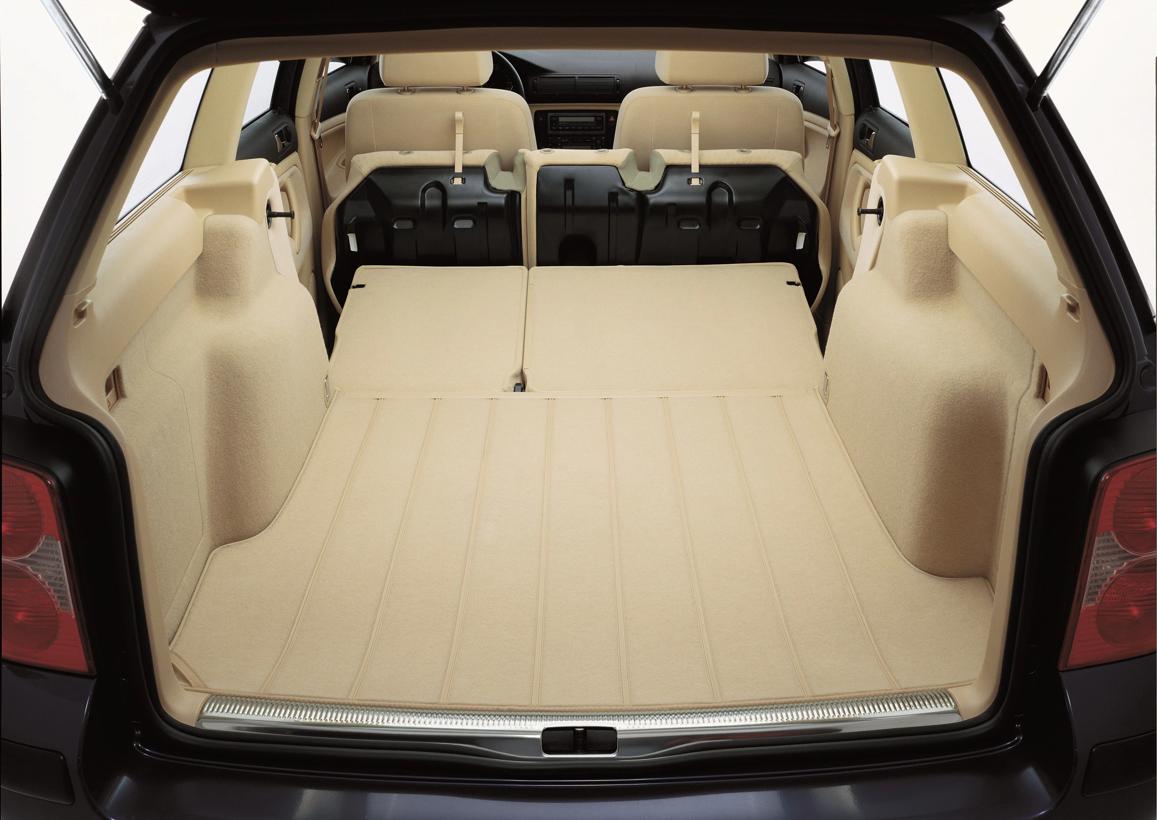 Kofferraum eines Autos mit umgeklappten Rücksitzen, die eine große, beige Ladefläche für Gepäck oder Frachten bieten.