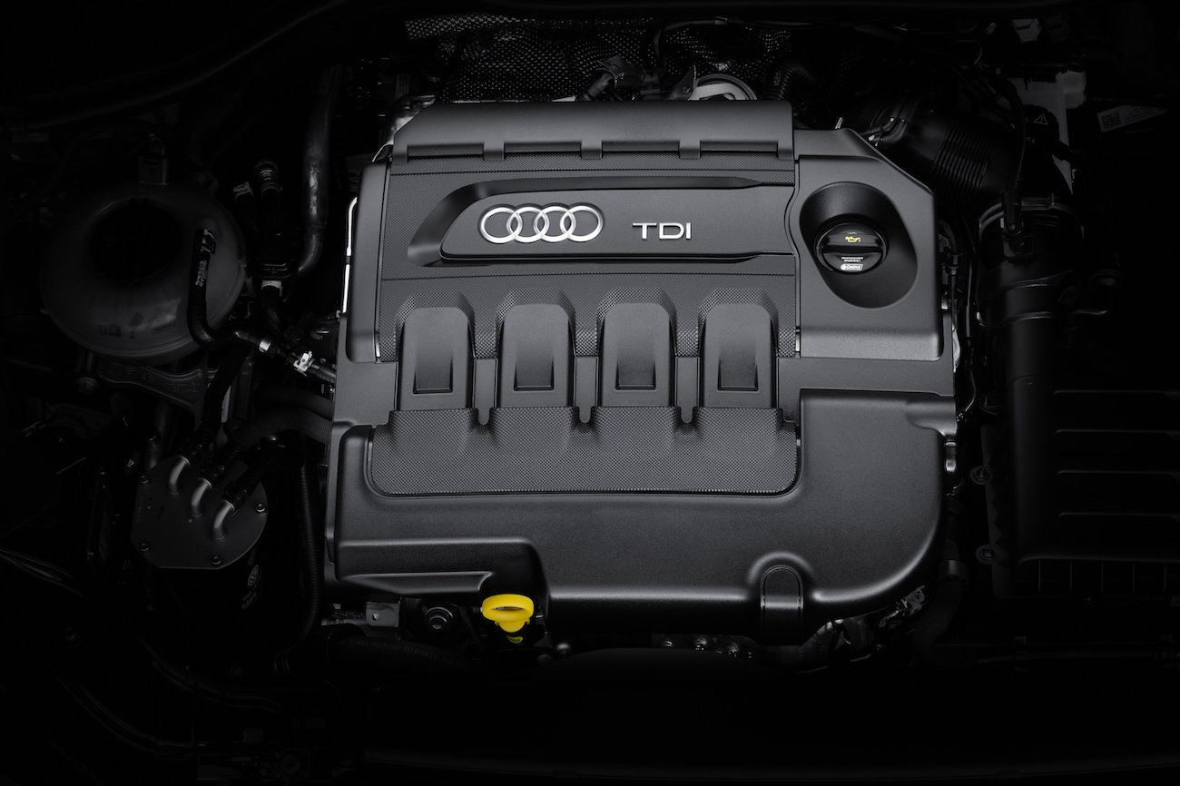 Motorraum eines Audi mit TDI-Dieselmotor, schwarzes Gehäuse, gelber Ölmessstabgriff und Markenlogo sichtbar.