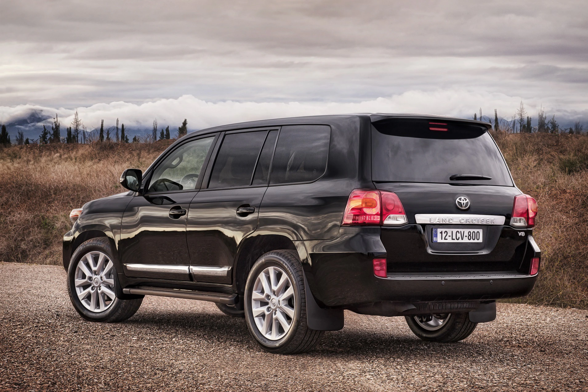 Schwarzer SUV, geparkt auf einem ländlichen Weg. Wolkenverhangener Himmel und kahle Landschaft im Hintergrund.