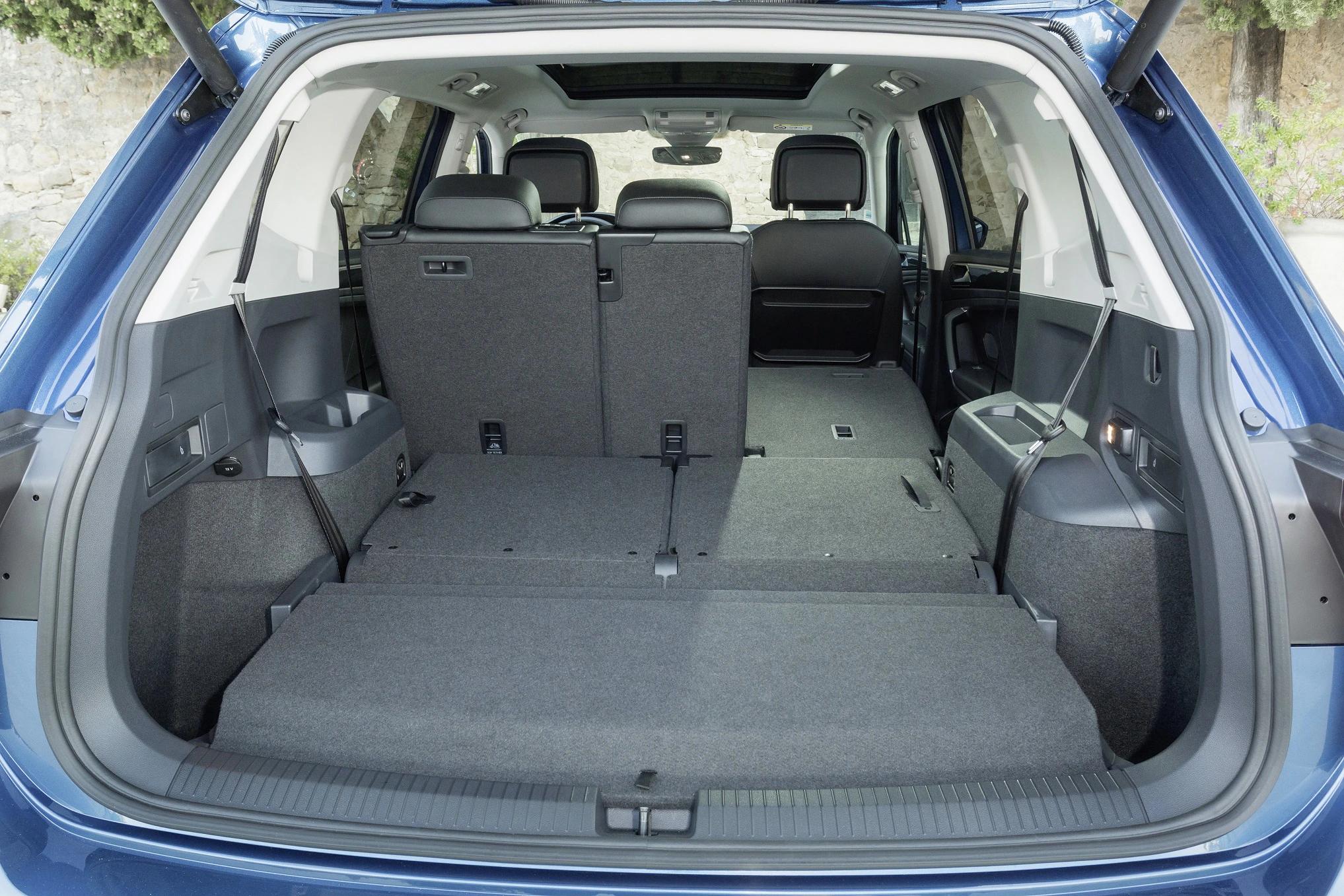 Kofferraum eines blauen SUV mit umgeklappten Rücksitzen, die einen großen, ebenen Laderaum schaffen. Kopfstützen hinten sichtbar.
