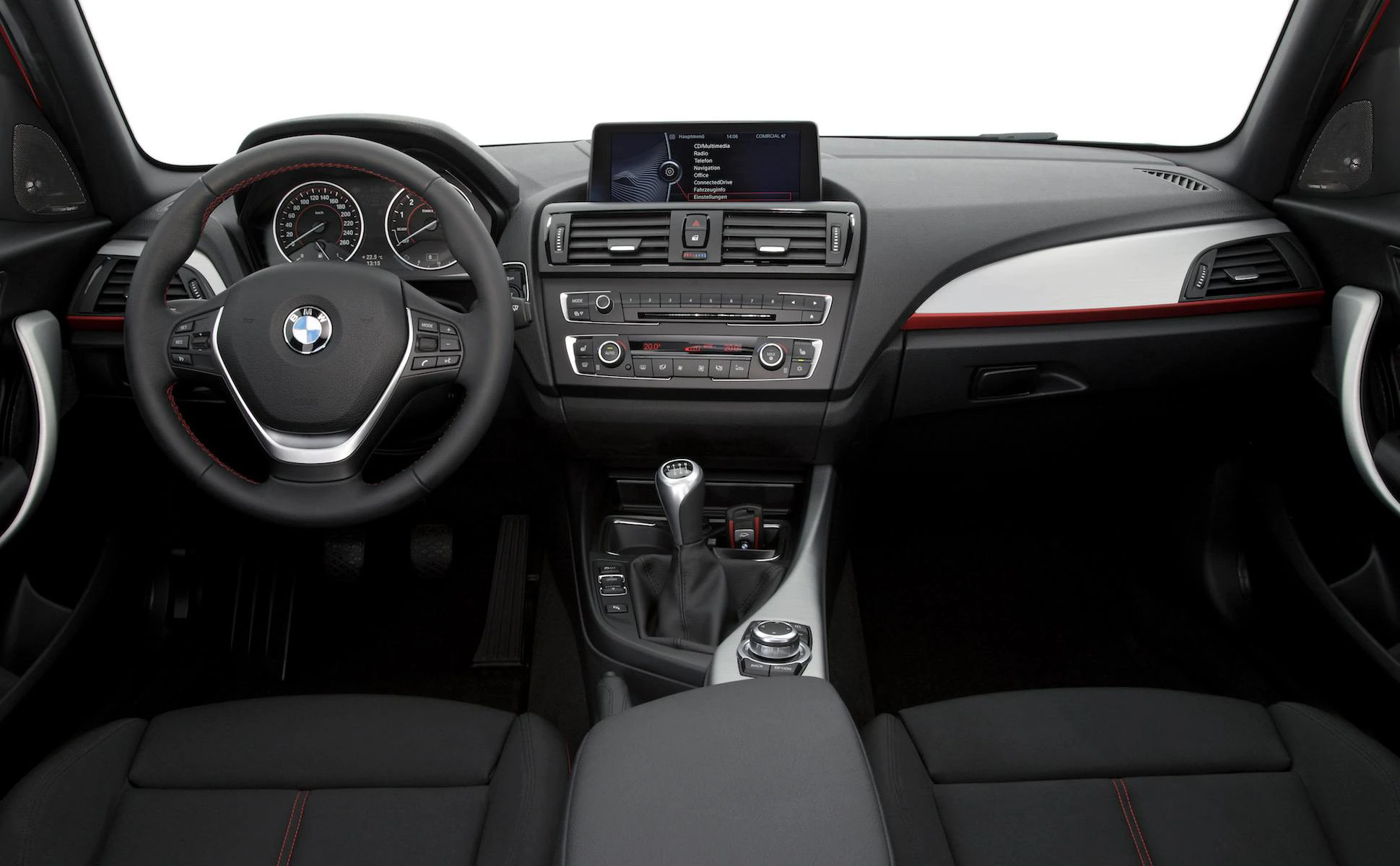 Innenraum eines BMW mit schwarzem Armaturenbrett, Lenkrad, Gangschaltung und Infotainment-Display. Modernes Design mit roten Akzenten.