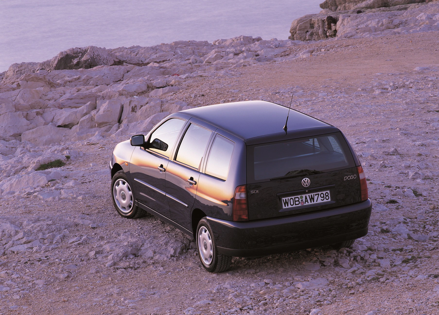 Ein schwarzer Volkswagen Polo steht auf felsigem Gelände bei Sonnenuntergang, mit reflektierendem Licht auf der Karosserie.
