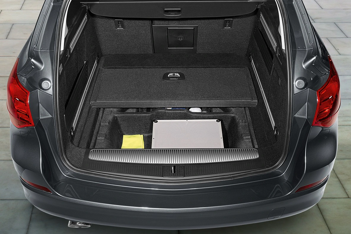 Offener Kofferraum eines Autos mit sichtbarem Stauraum, darunter ein Fach mit einer gelben Tasche und einer silbernen Box.