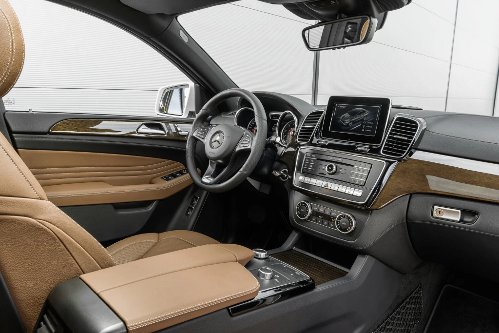 Innenraum eines luxuriösen Autos mit braunen Ledersitzen, einem Multifunktionslenkrad und einem zentralen Touchscreen-Display.