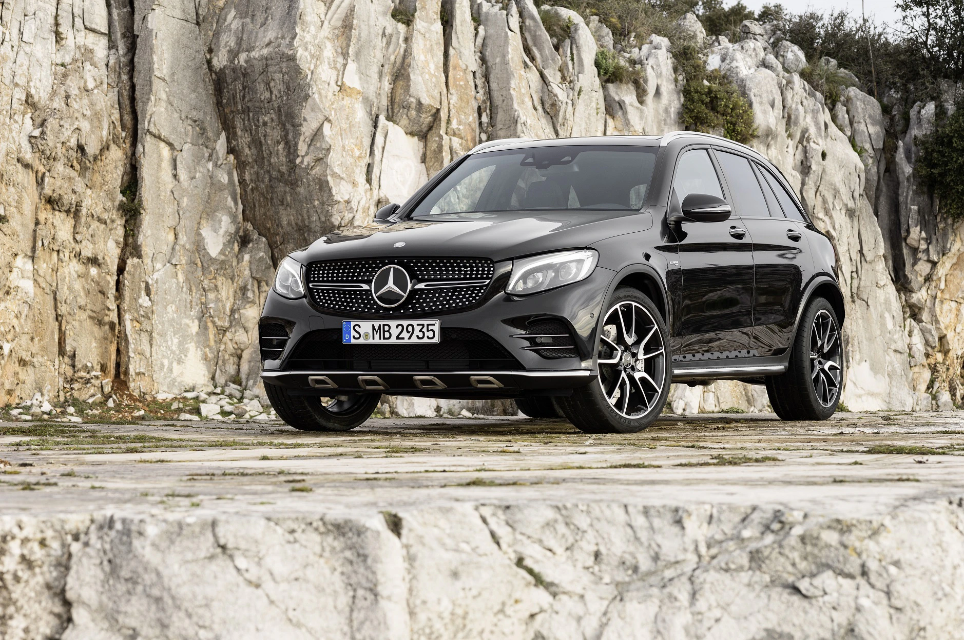 Grauer Mercedes-Benz SUV parkt vor beeindruckenden Felsformationen. Elegantes Design und stilvolle Leichtmetallfelgen.