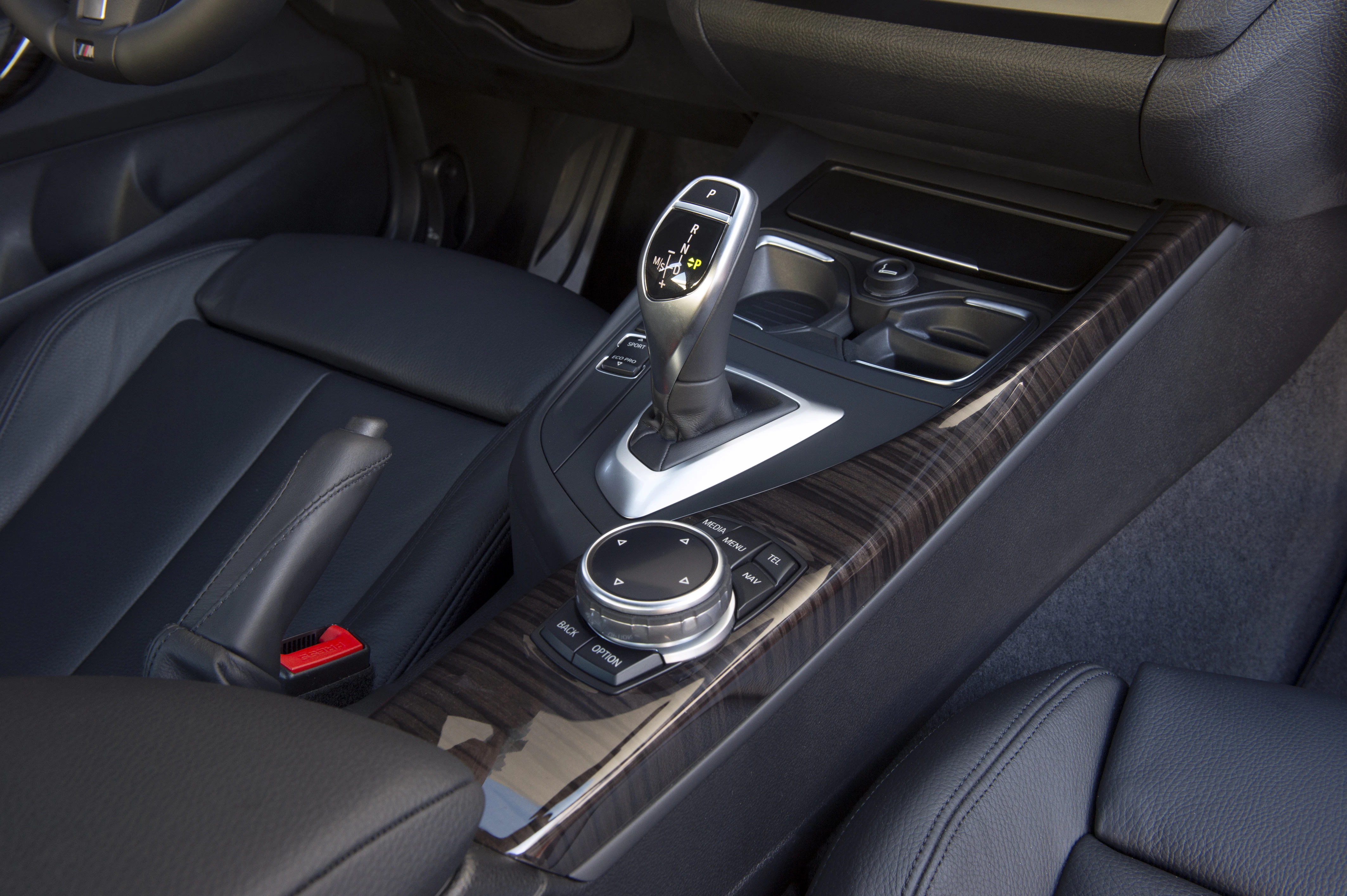 Nahaufnahme einer Autokonsole mit Schalthebel, Steuerknopf und Lederverkleidung in einem modernen Fahrzeuginterieur.