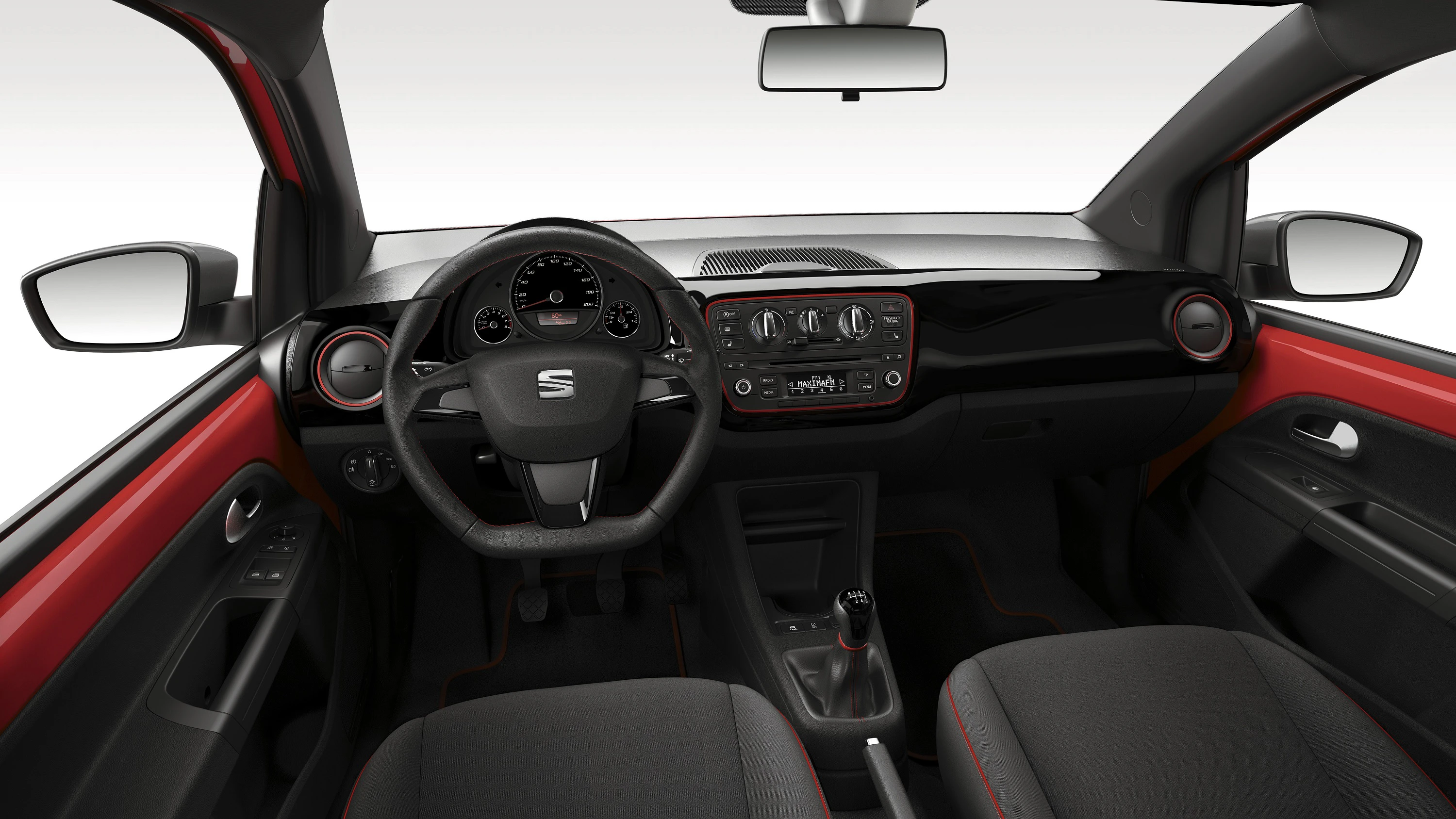 Innenansicht eines Autos mit schwarzem und rotem Armaturenbrett, Lenkrad mit Markenlogo, digitalem Tacho und manueller Gangschaltung.