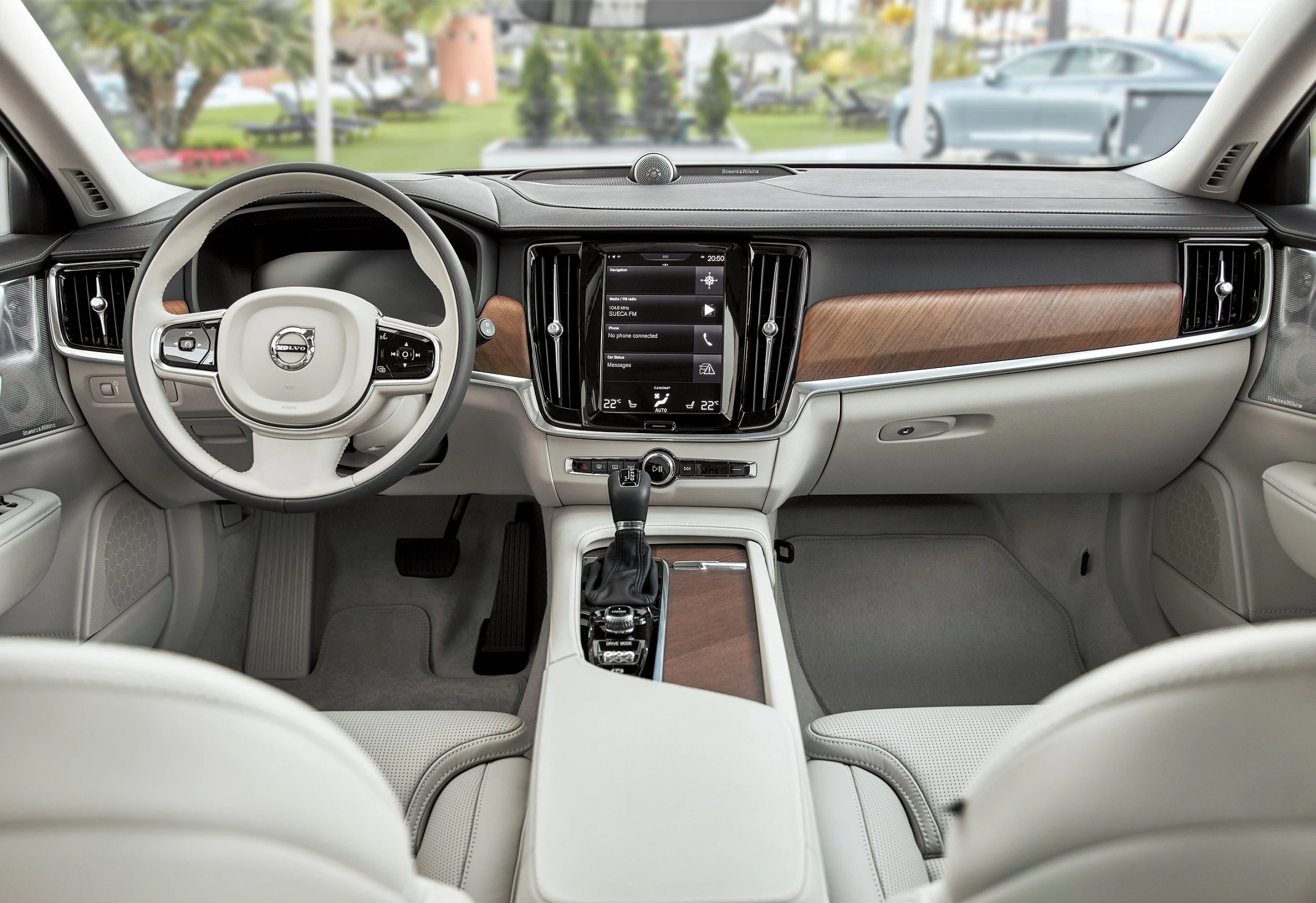 Lenkrad und Armaturenbrett eines modernen Autos mit Holz- und Lederausstattung. Das Display zeigt verschiedene Fahrzeugoptionen.