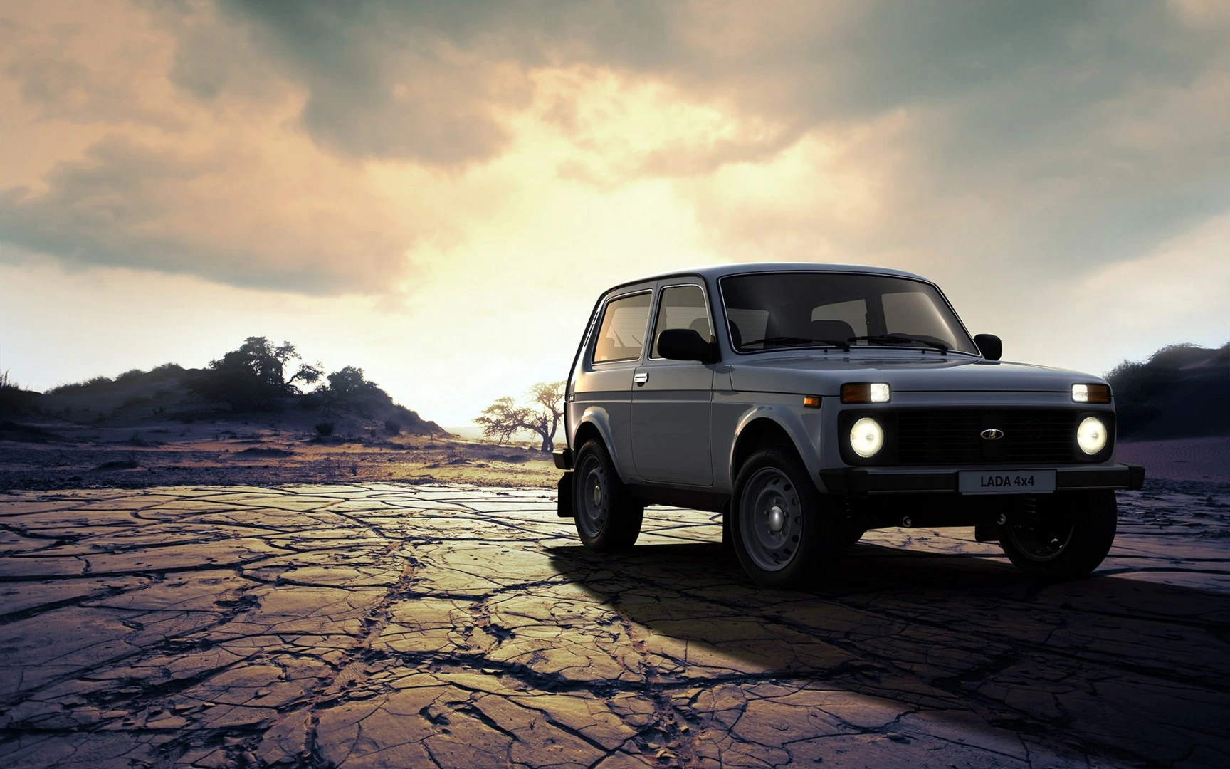 Ein Lada 4x4 Offroad-Fahrzeug steht auf einer trockenen, rissigen Ebene vor einem dramatischen Himmel bei Sonnenuntergang.