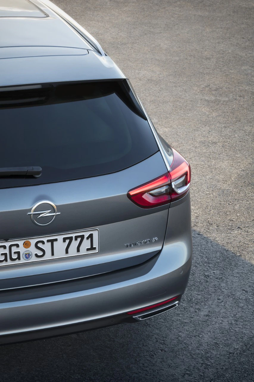 Rückansicht eines grauen Opel-Fahrzeugs auf grauem Untergrund. Sichtbar sind Rückleuchte, Heckscheibe und Nummernschild.