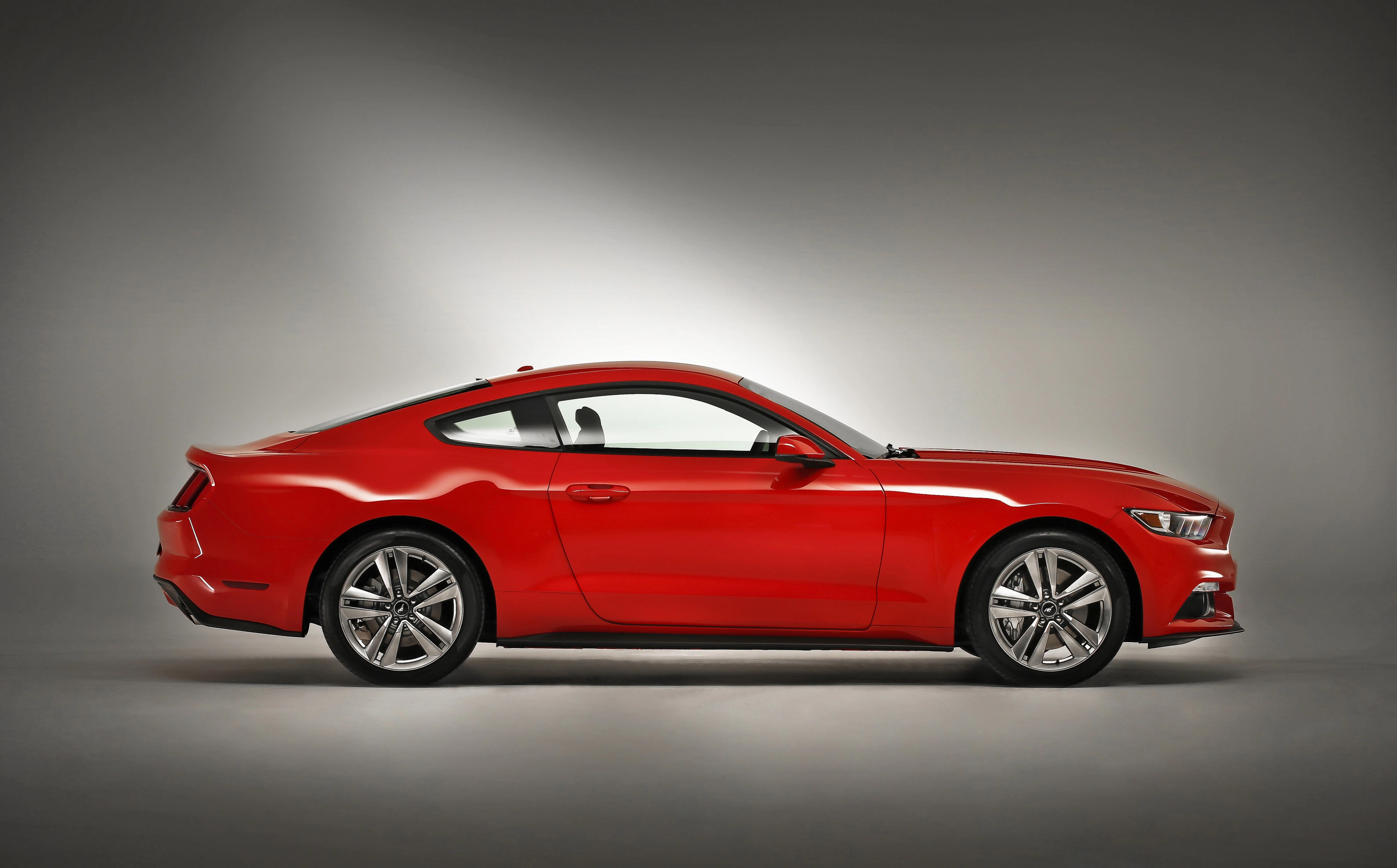 Rotes Sportcoupé vor grauem Hintergrund in Seitenansicht, mit eleganten Linien und glänzender Oberfläche.