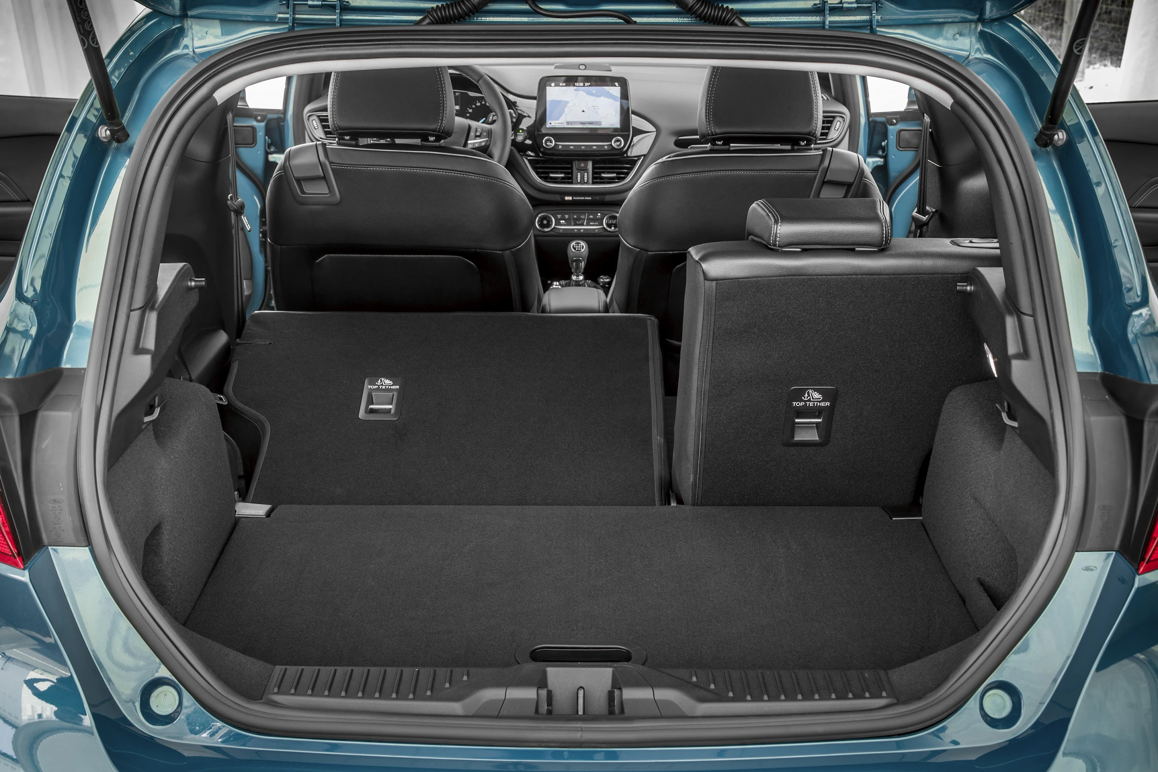 Blick in einen Kofferraum eines Autos mit umgeklappten Rücksitzen. Moderner Innenraum mit Sicht auf das Armaturenbrett und Infotainmentsystem.