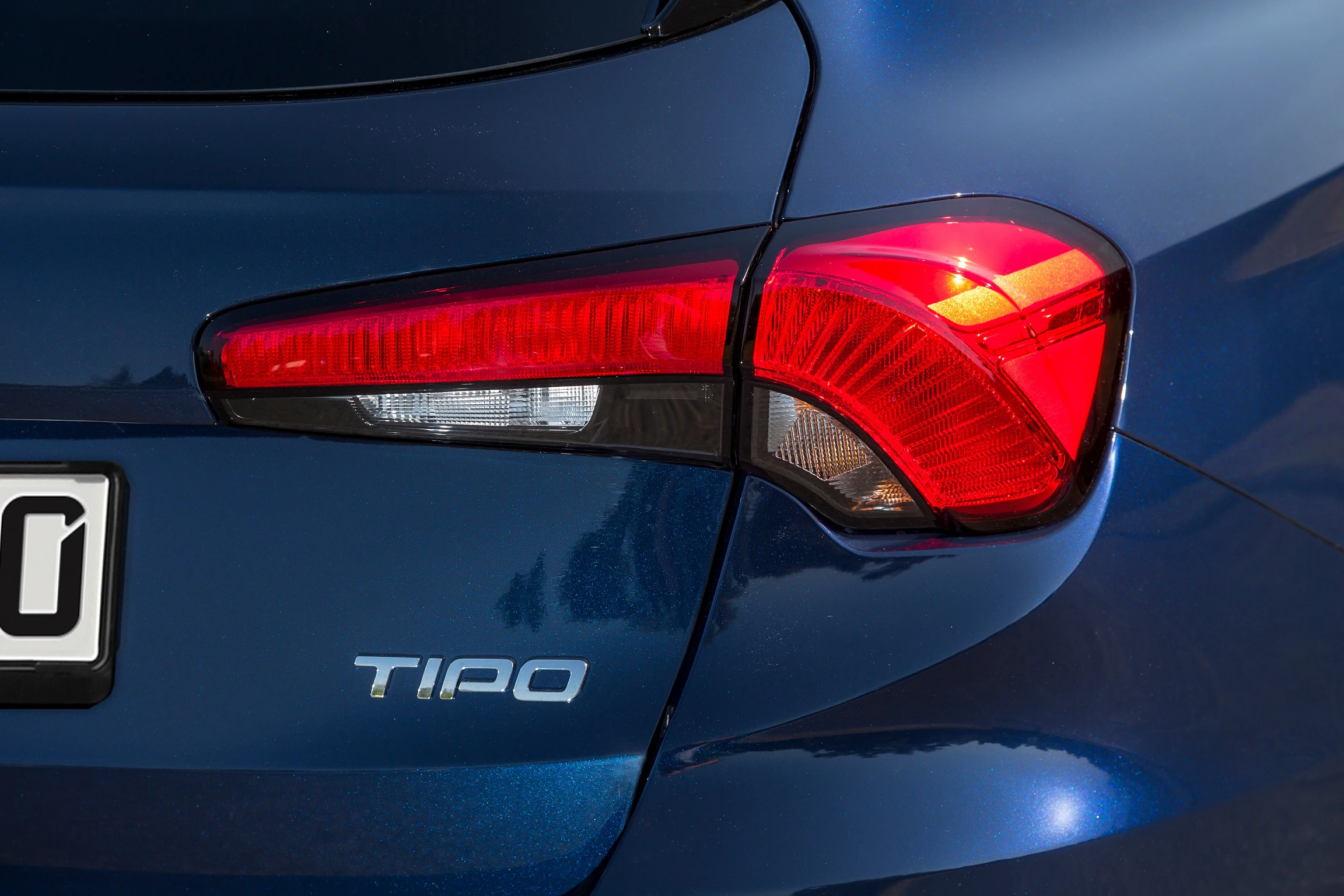 Nahaufnahme eines blauen Autos mit dem Schriftzug "Tipo" und einem deutlichen Rücklicht auf der rechten Seite.