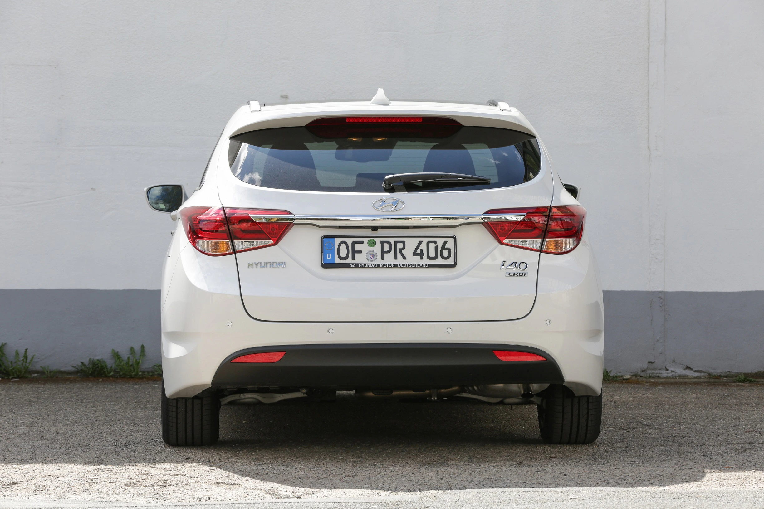 Weißer Hyundai i40 Kombi, hinten zu sehen, parkt vor einer grauen Wand. Nummernschild: OF PR 406.