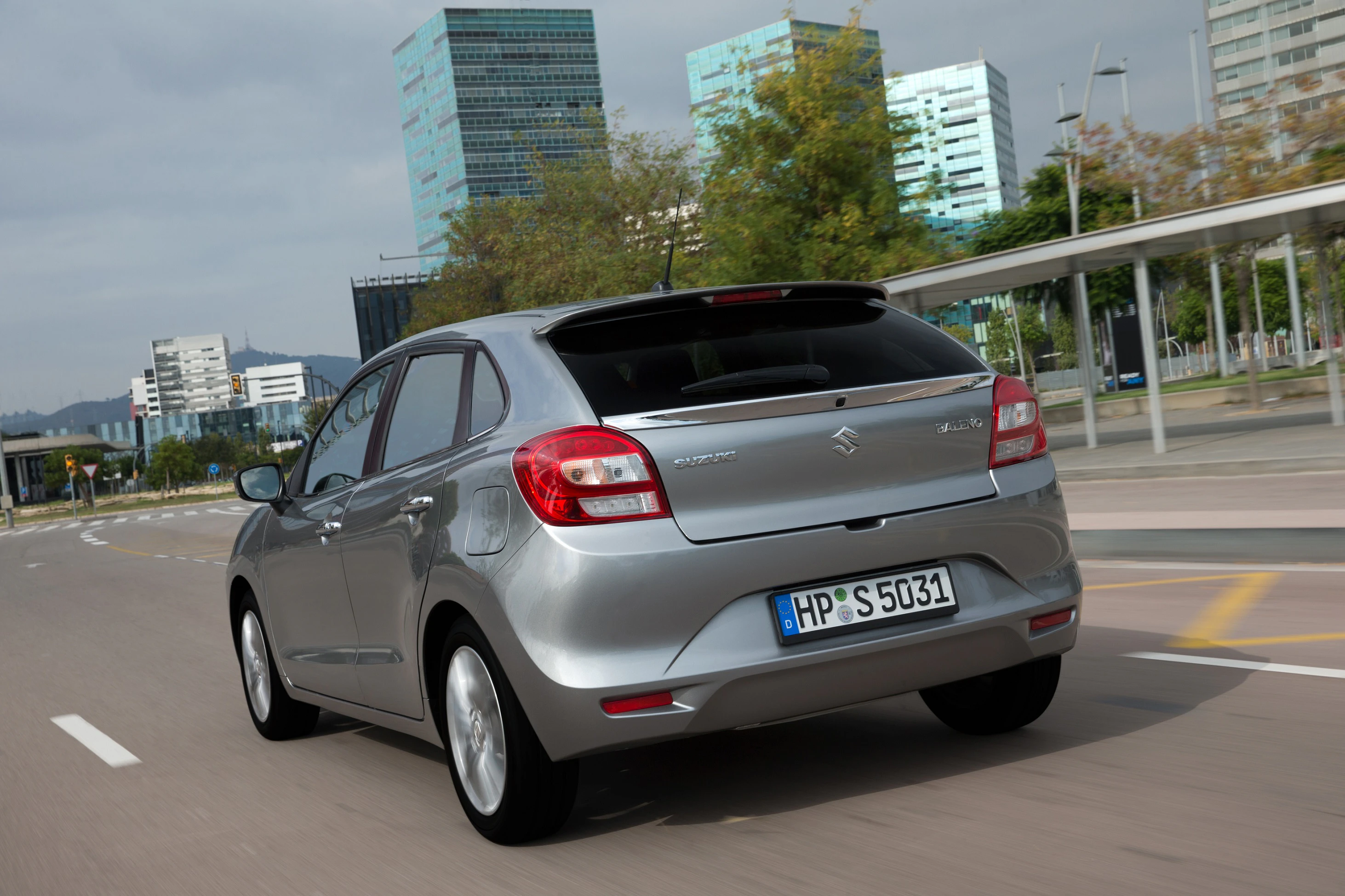 Silberner Citroën C3 von hinten auf einer Straße, moderne Gebäude im Hintergrund bei Tageslicht.