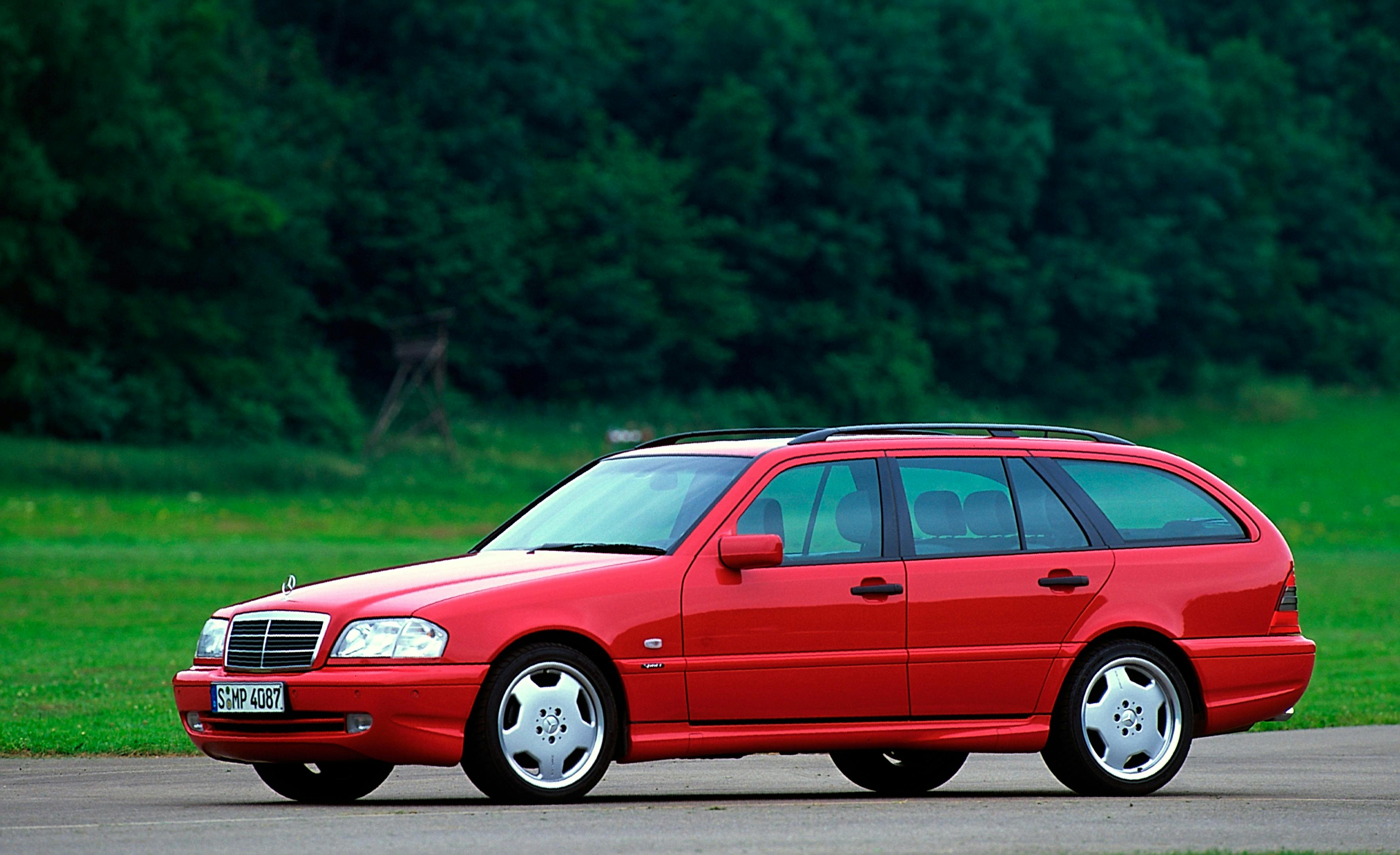 Roter Kombi Mercedes-Benz auf einer Straße vor einem grünen Wald im Hintergrund.